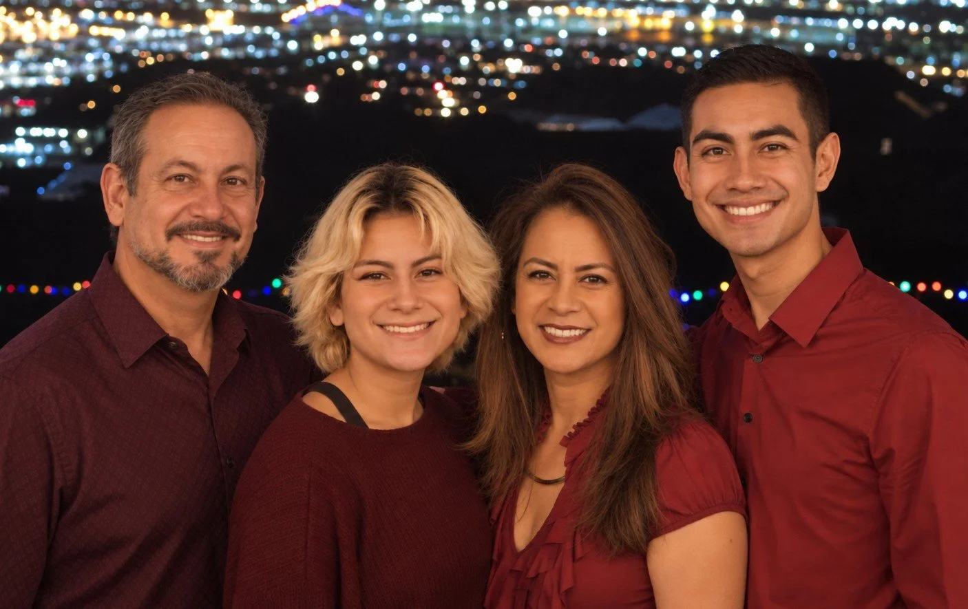 Group of four people smiling at night with city lights in the background.
