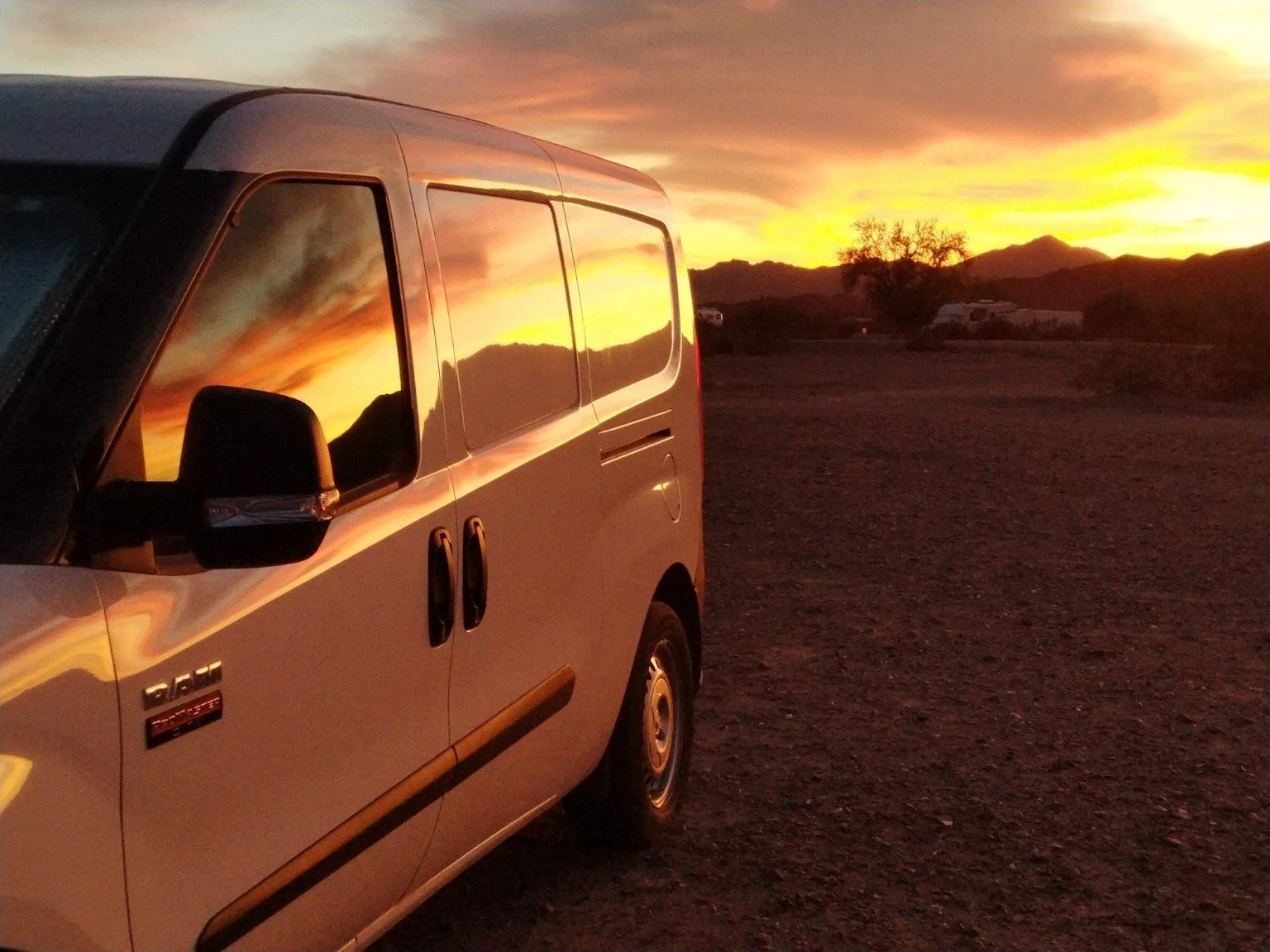 Jo’s white van reflecting a dramatic desert sunset