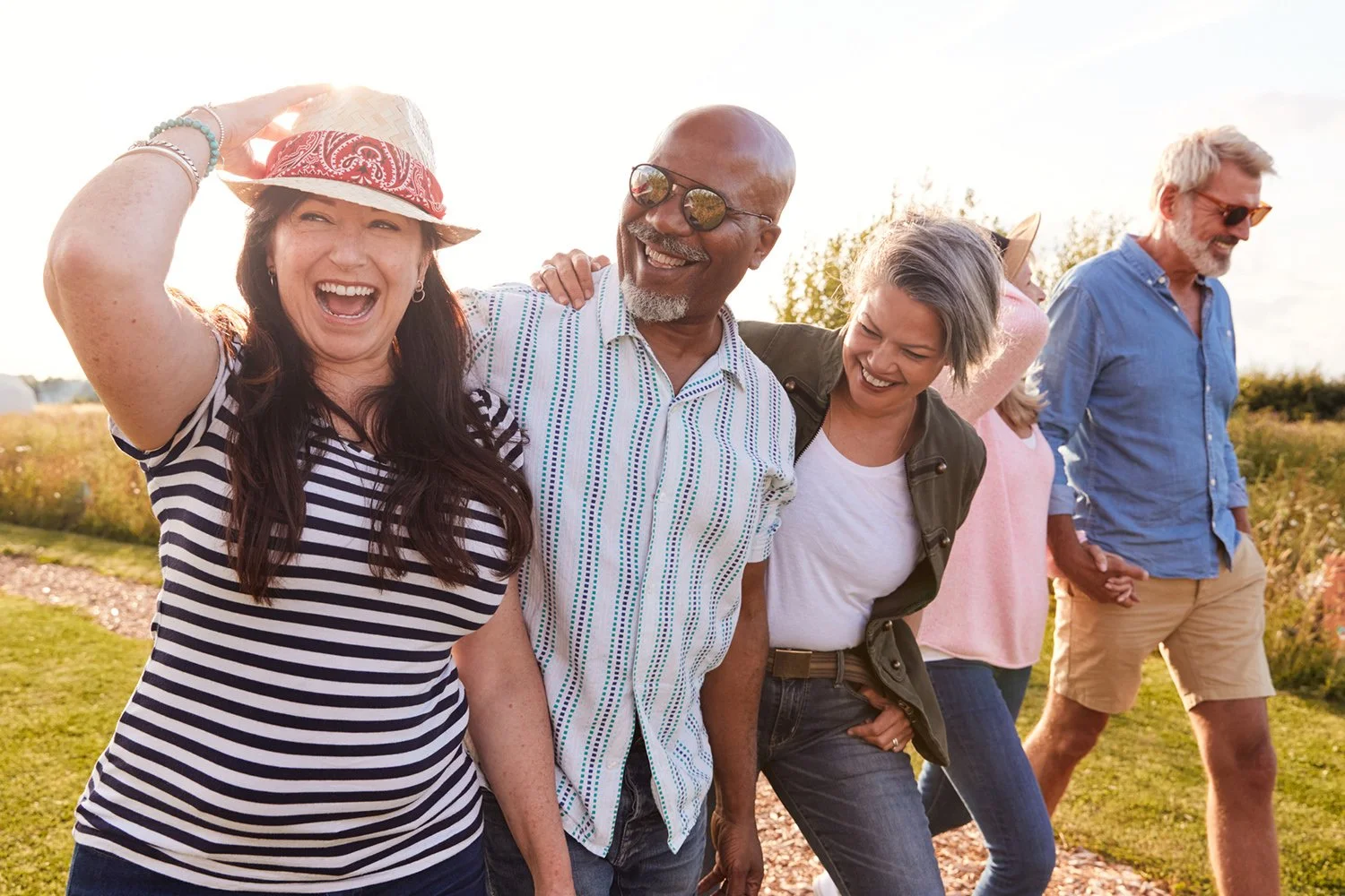 Group of diverse adults laughing together outdoors. The older man in the picture is able to interact and communicate better with his friends after receiving speech therapy, occupational therapy, and physical therapy for adults in Honolulu, HI