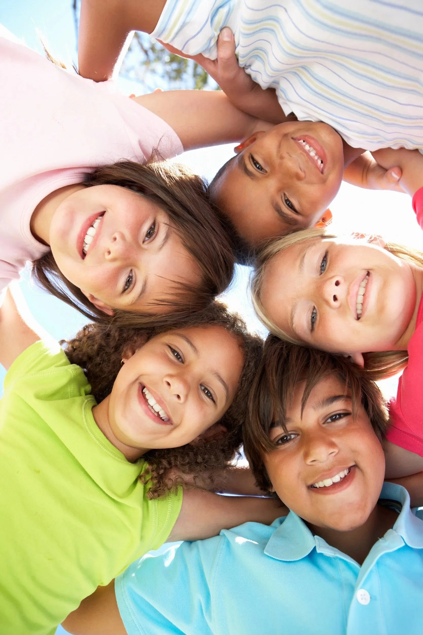 Six smiling children huddle together for a sunny outdoor photo; all children have improved communication skills thanks to Hawai'i Therapy Network in Honolulu, HI