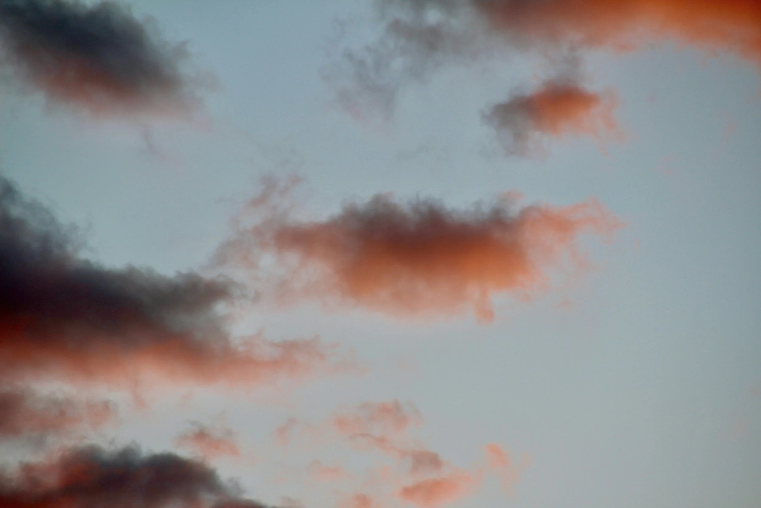 Colorful clouds in a sky with hints of orange and dark gray, possibly during sunset or sunrise.
