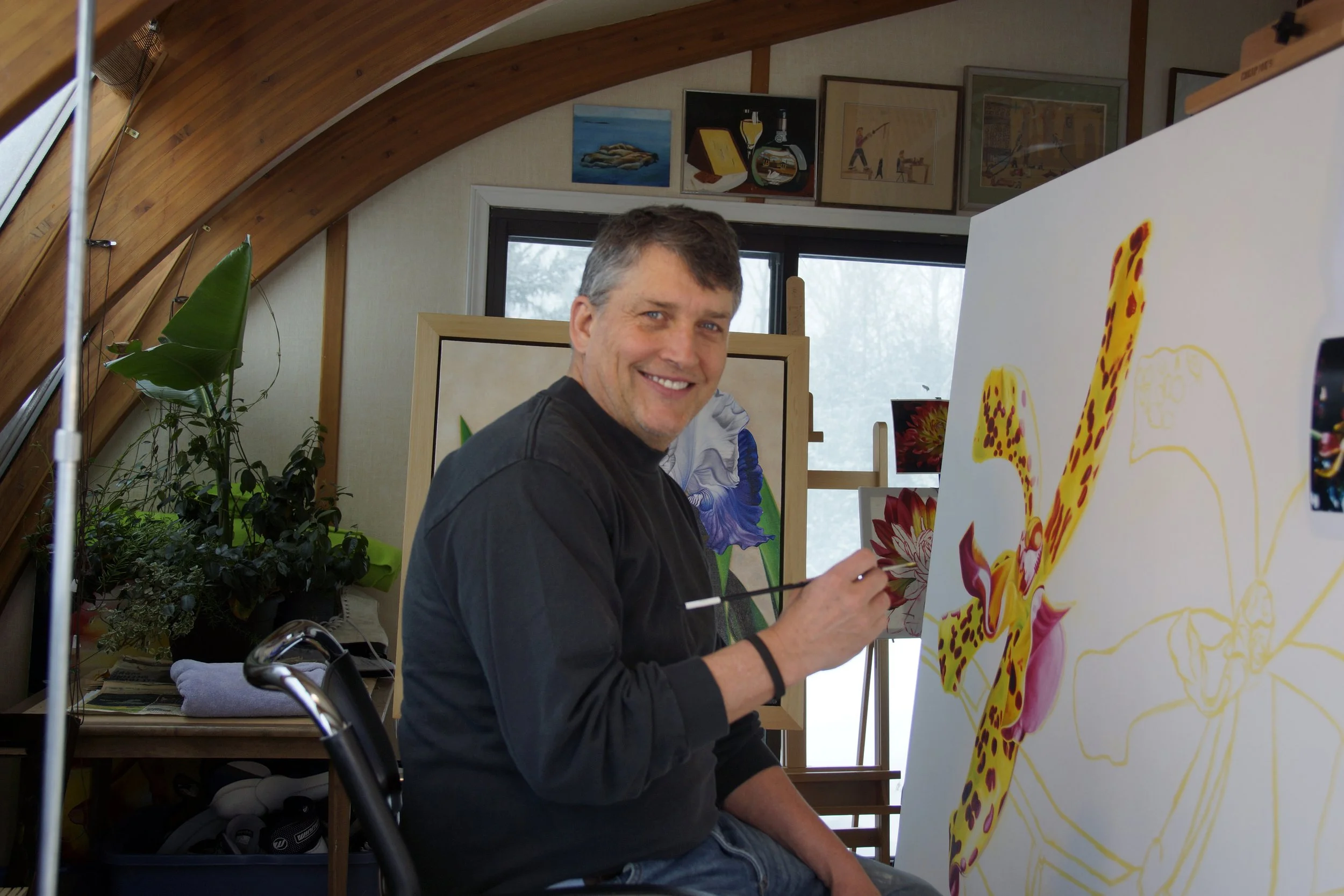 Bert Liverance painting a colorful floral artwork on a large canvas in a home studio