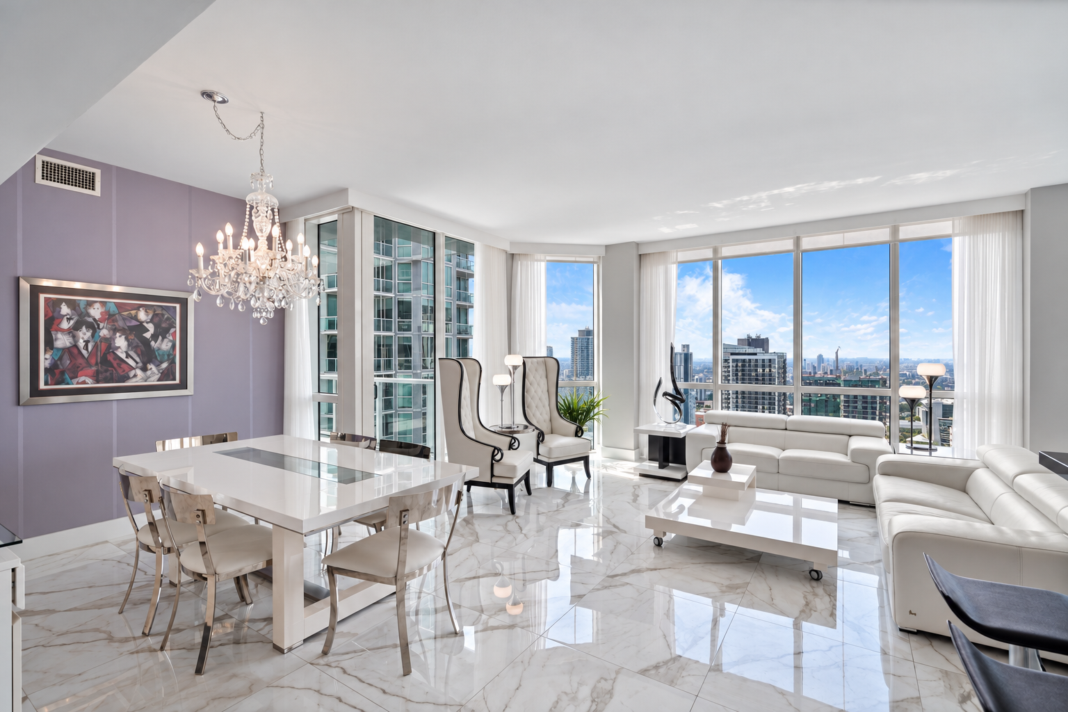 Modern living room with white leather sectional sofa, high-backed chairs, a glass-top dining table, large windows with city views, a chandelier, and marble floors.