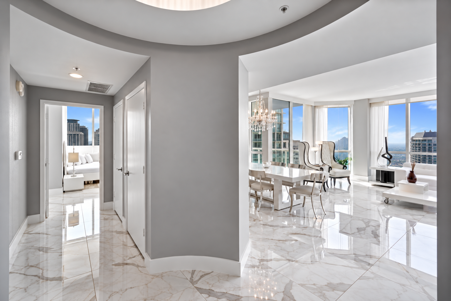 Bright modern apartment living room with large windows, white furniture, and decorative items, showcasing city skyline views.