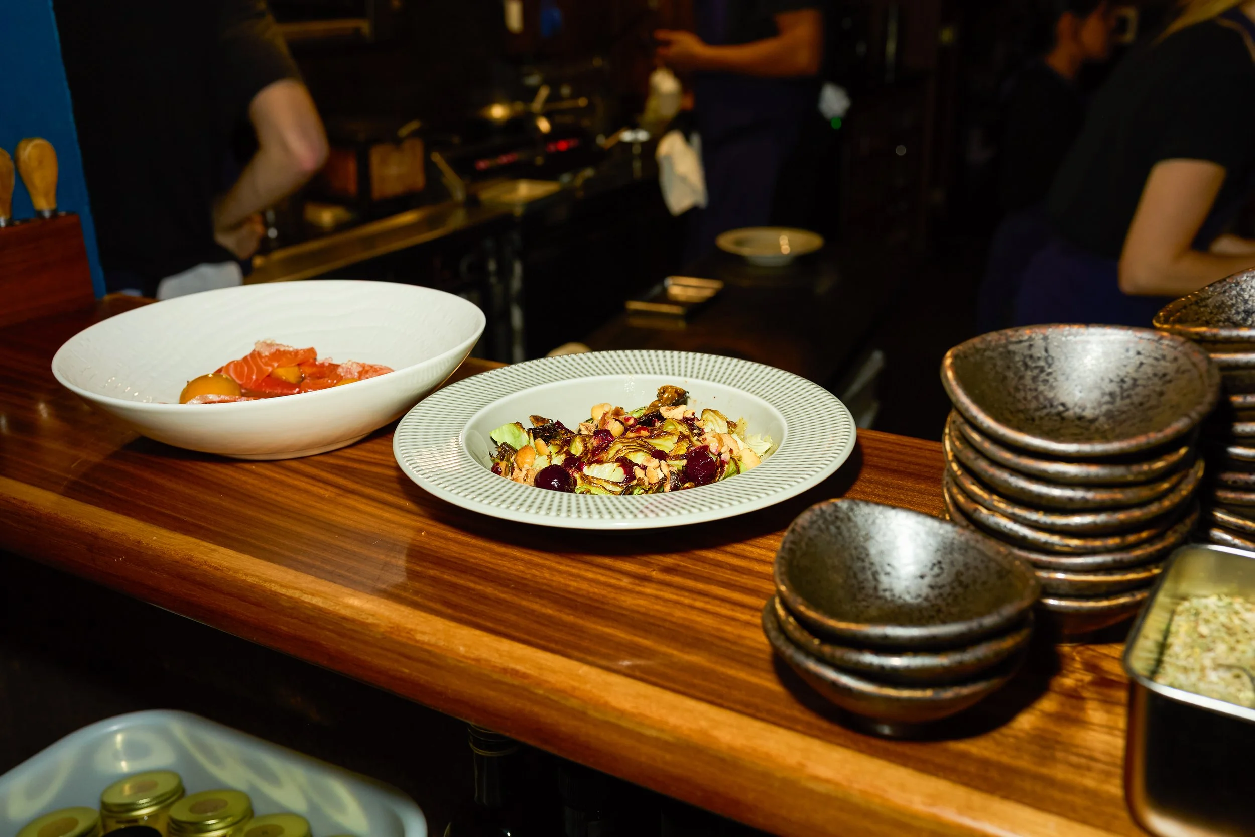 Gourmet dishes, including salmon and a colorful vegetable salad, served on a wooden restaurant table