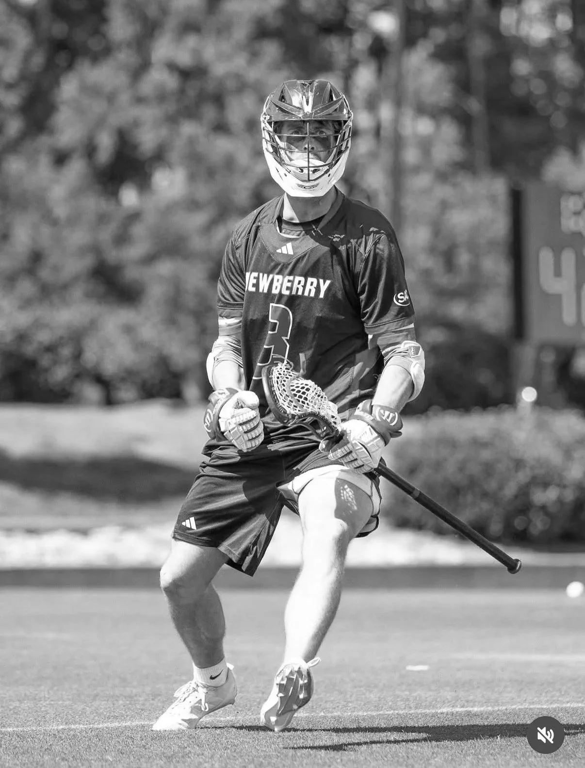 A lacrosse player wearing a helmet, jersey with 'Newberry' and number 3, shorts, gloves, and holding a lacrosse stick, on a field during a game.