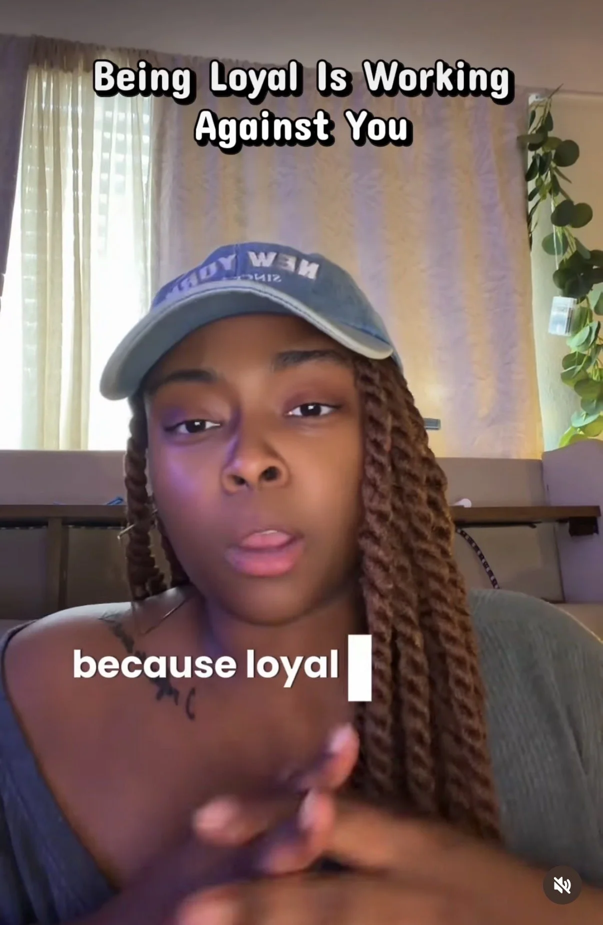 Woman with braids wearing a baseball cap speaking in front of a window with curtains, with text overlay reading 'Being Loyal Is Working Against You because loyal'.