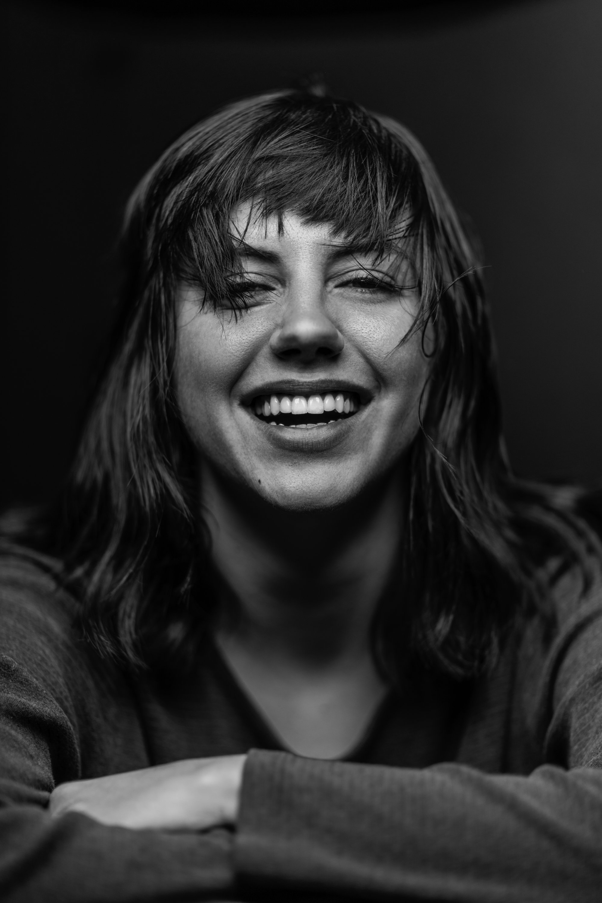 Black and white close-up portrait of a woman with wet hair, smiling with eyes slightly squinted.