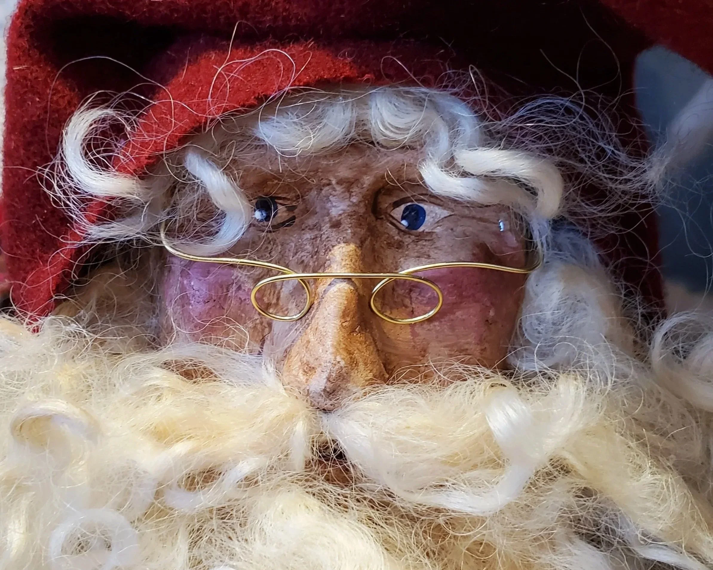 Close-up of a handmade Old World Santa with a red hat, wire-rimmed glasses and a curly white beard.