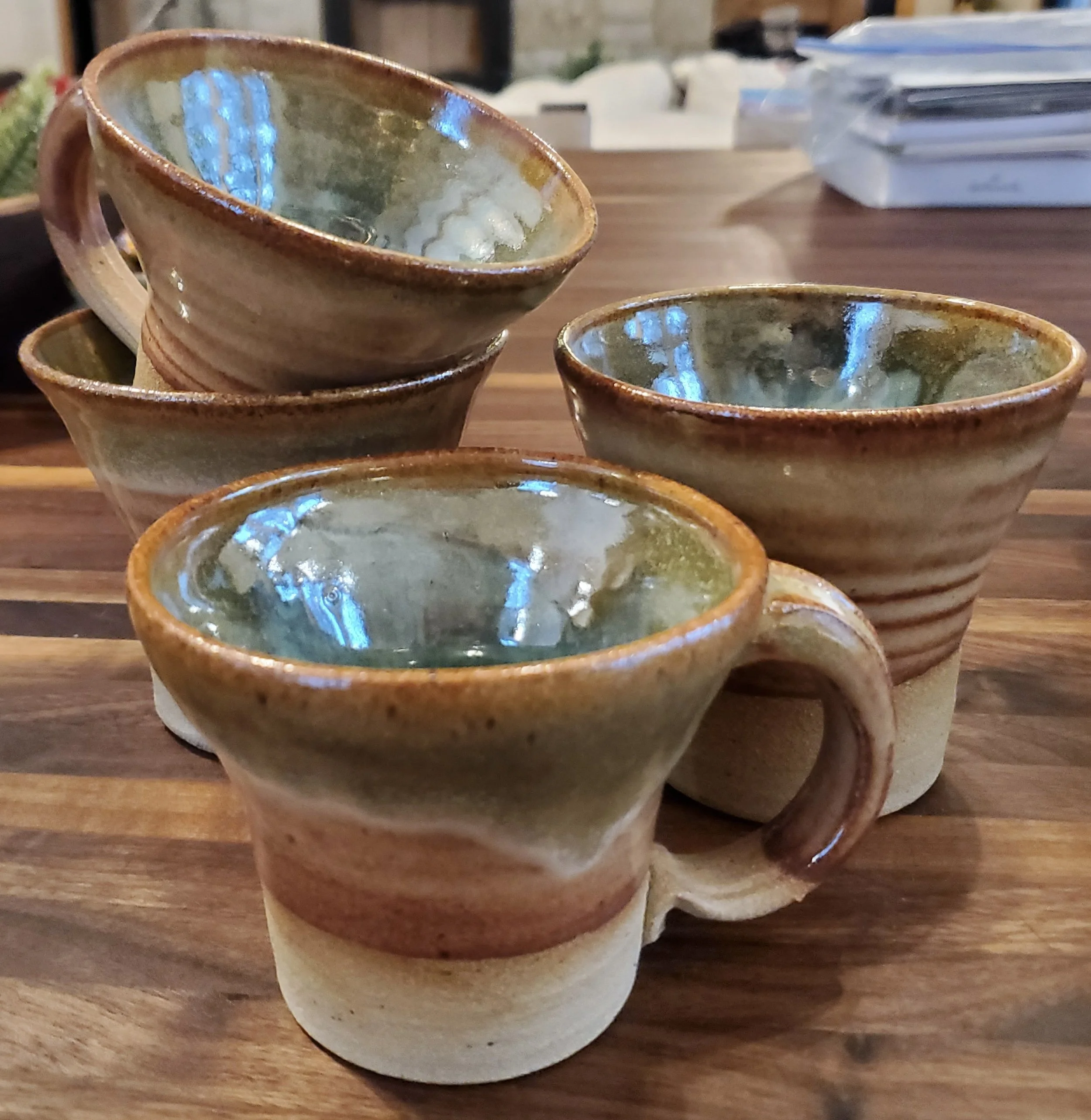 Handmade pottery cups with warm brown exteriors and glossy blue-green interiors by Cate Hauser.