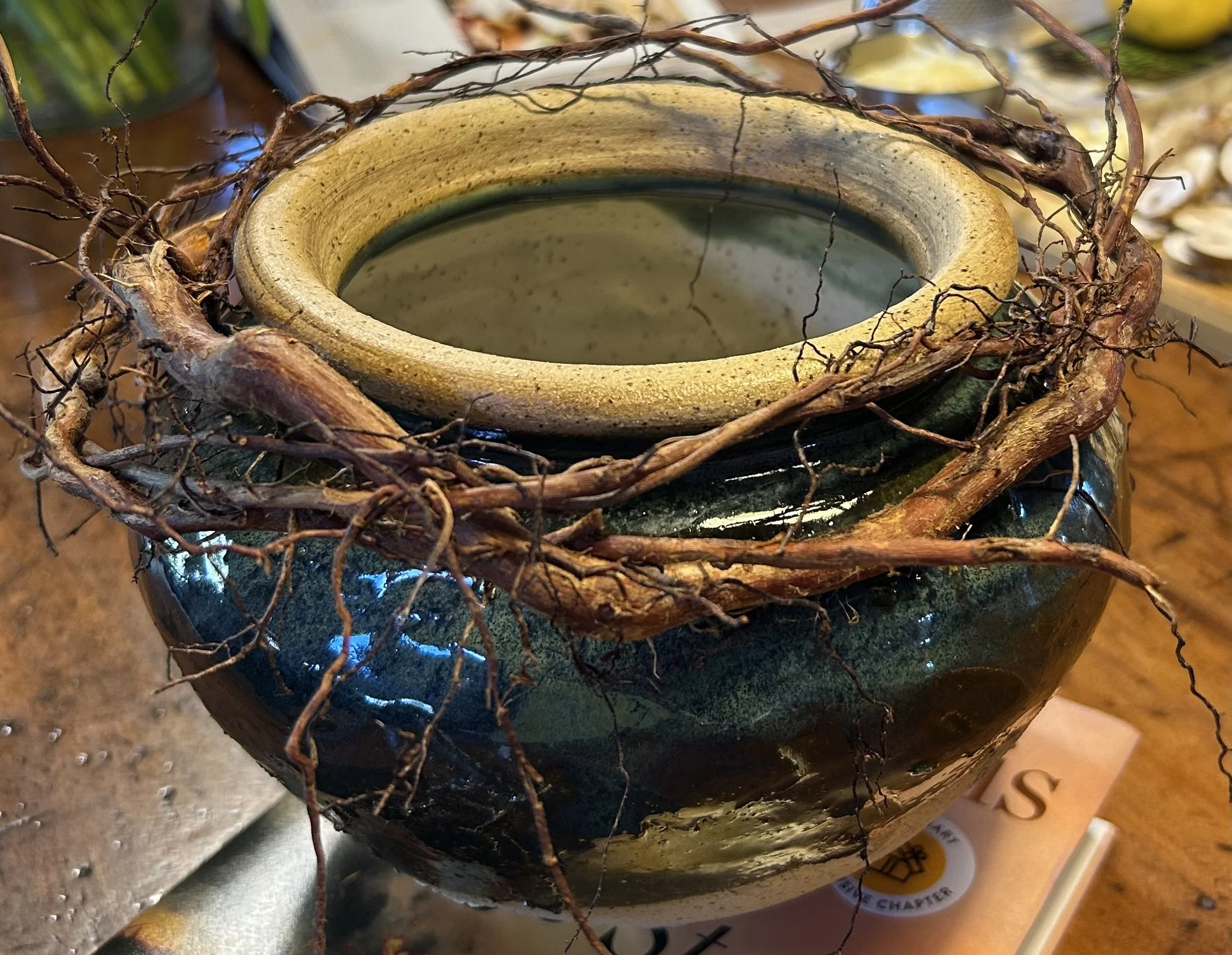 Handmade blue-green glazed ceramic vessel surrounded by a nest of intertwined natural branches sourced from Lake Superior.