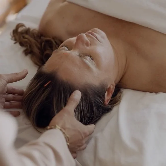 Woman lying on a massage table while a therapist gently massages her scalp