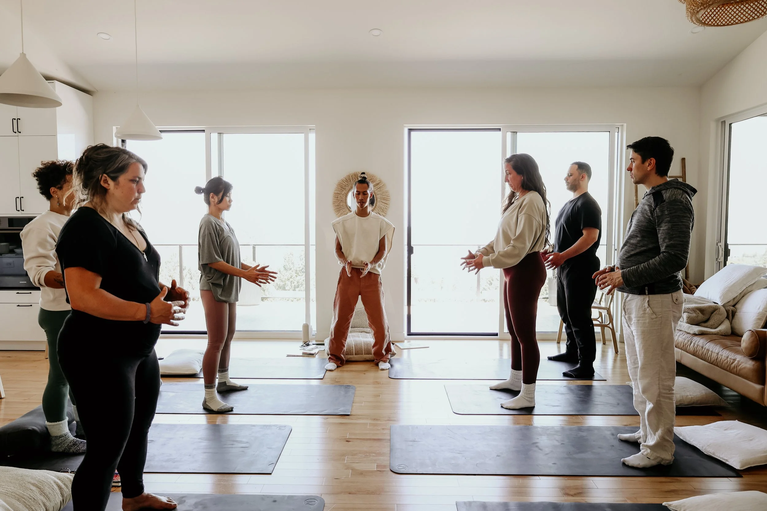 Group of people practicing qigong on mats in a bright living room