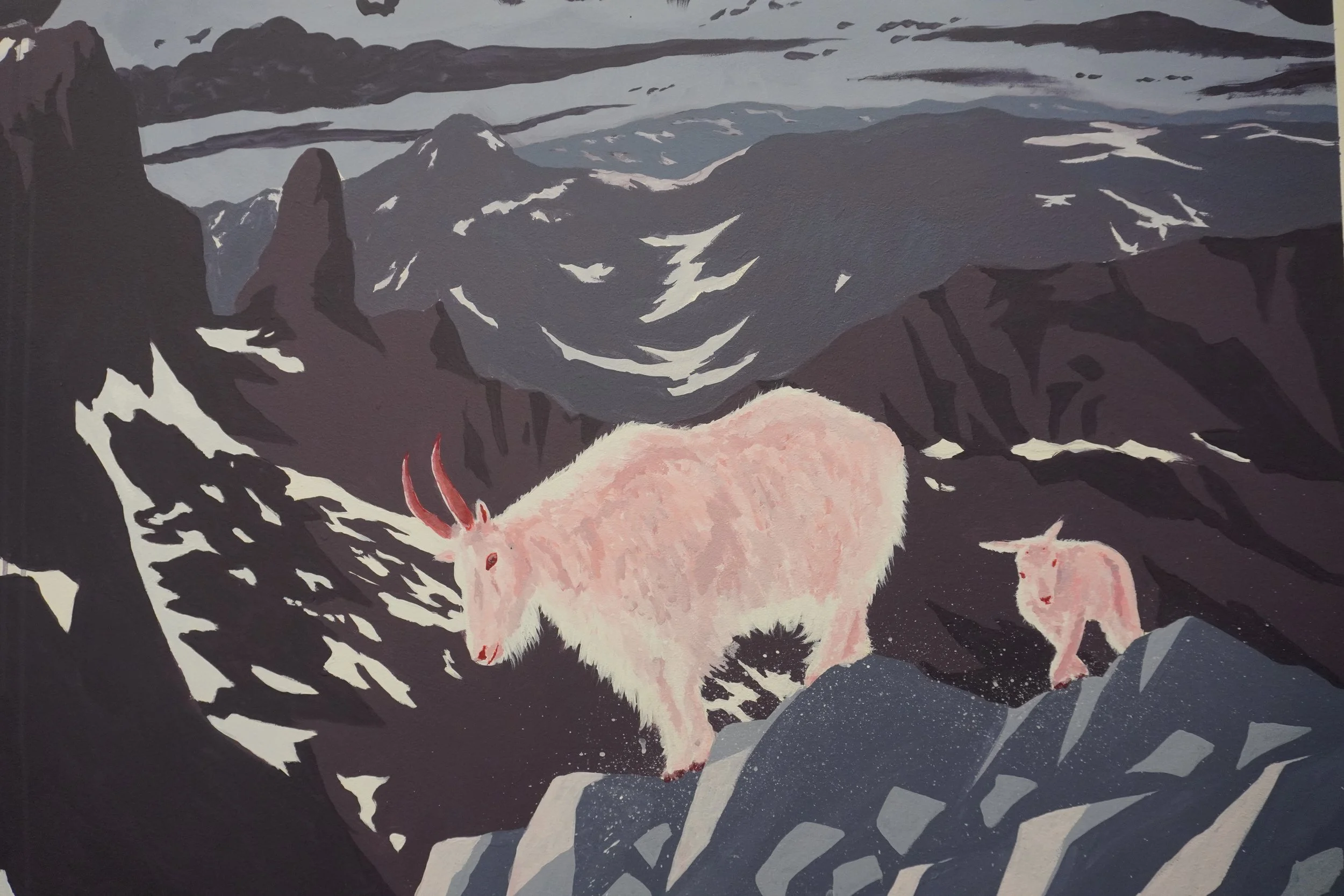 Detail photo of a mother mountain goat and kid navigating a snowy, rugged mountain landscape.