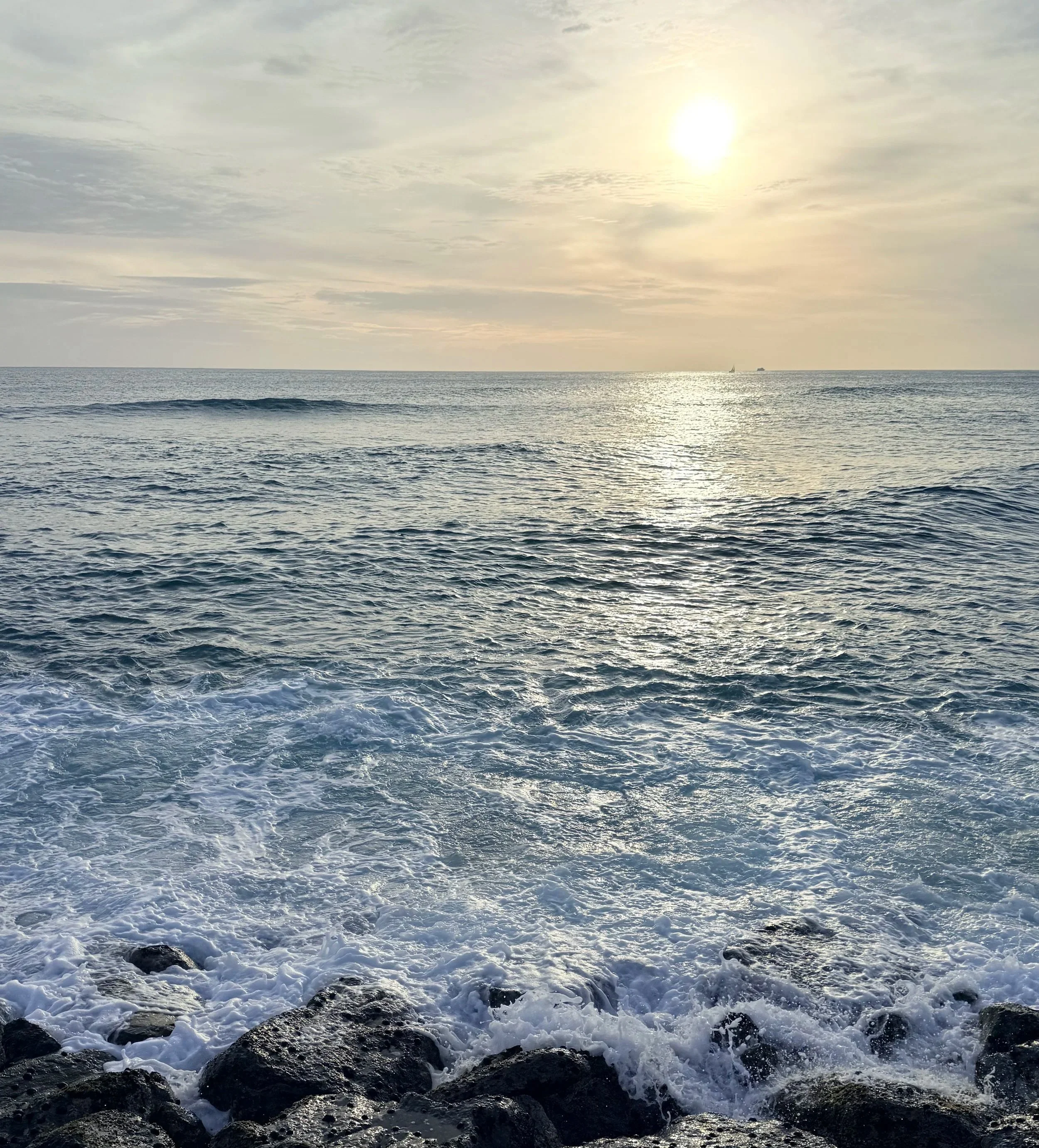 Sunset over ocean waves breaking on dark rocks