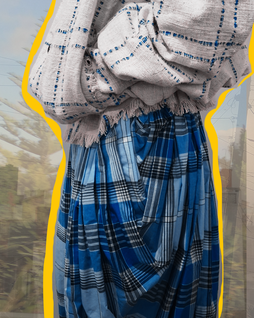 Close-up of clothing: a white, fringed shawl with blue stripped patterns and a blue plaid skirt wrapped around the waist.