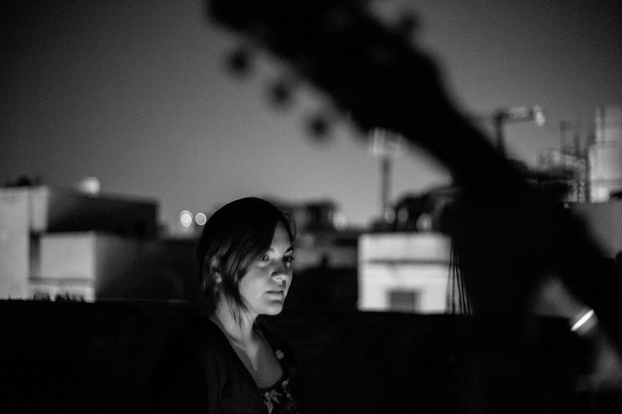 Portrait of Sara Vera, brand designer, art director and illustrator, wearing glasses outdoors at dusk with a softly blurred city background.