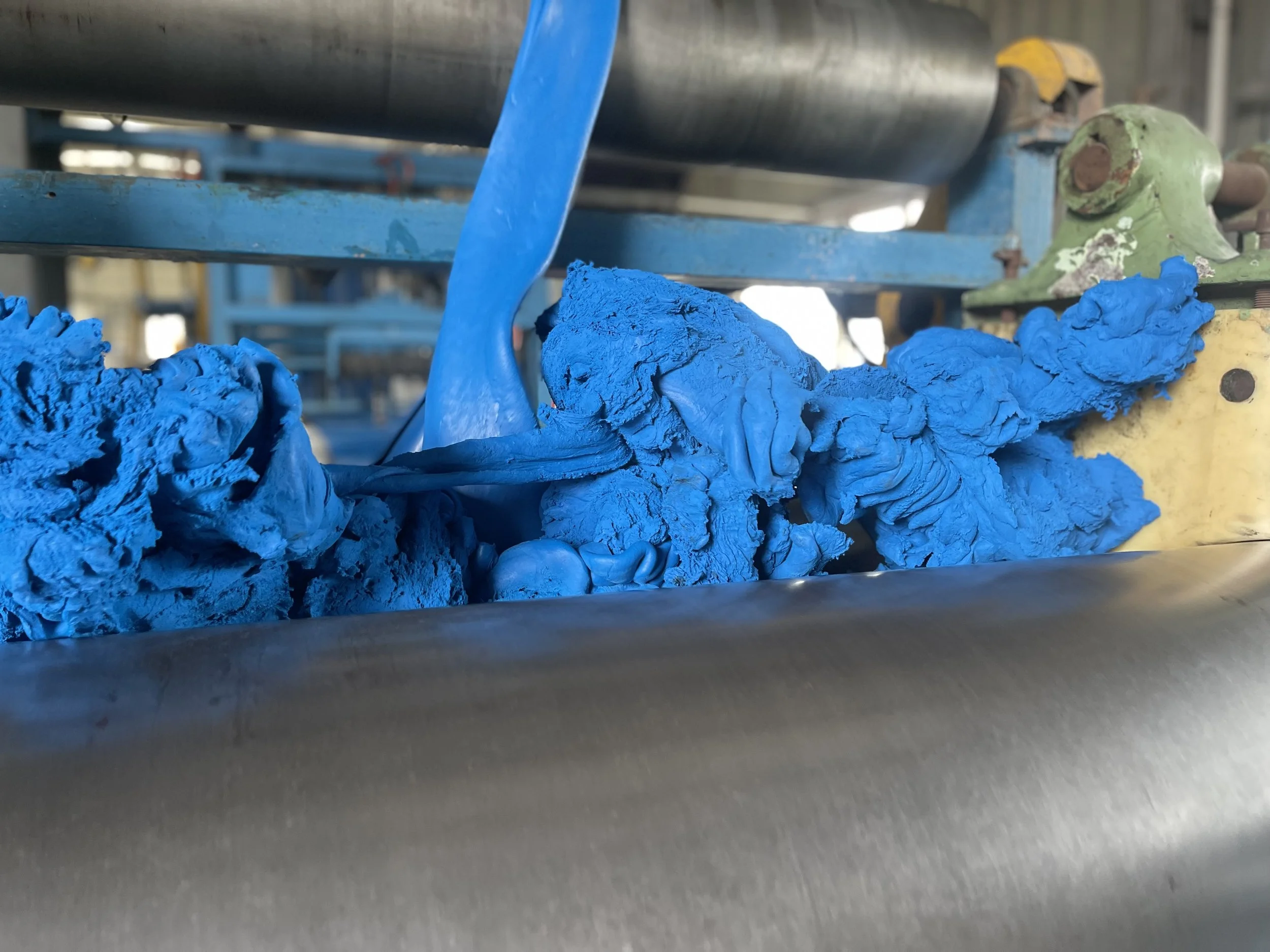 Close-up of rubber and metal machine parts with blue rubber material in the foreground.