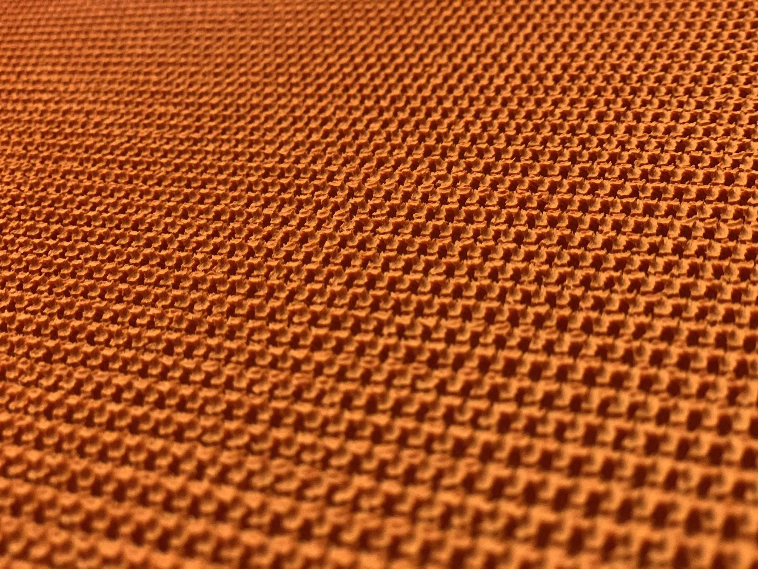 Close-up of the textured orange surface of a rough top conveyor belt.