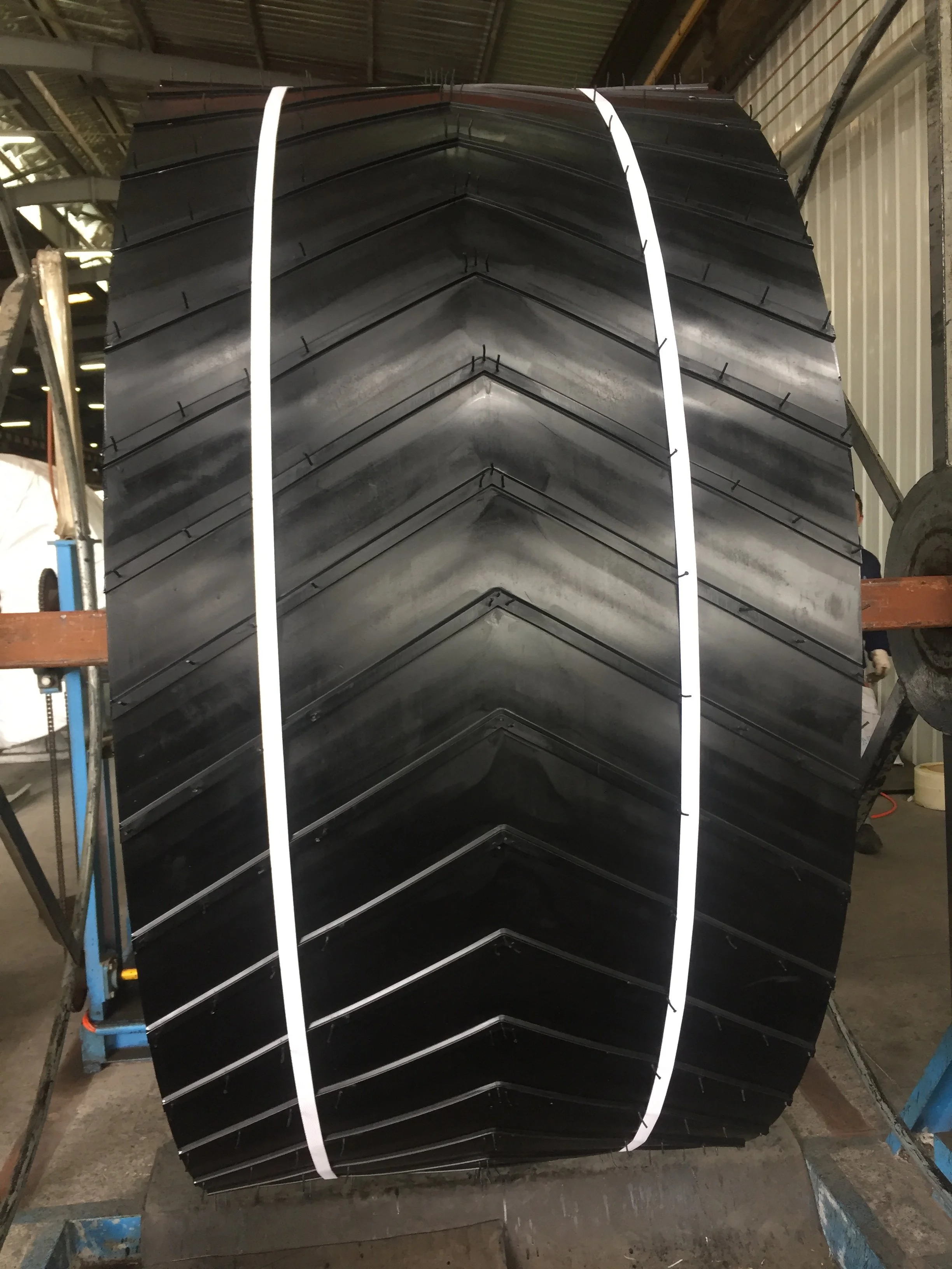 A conveyor belt with profile cleats on a storage rack in a factory.