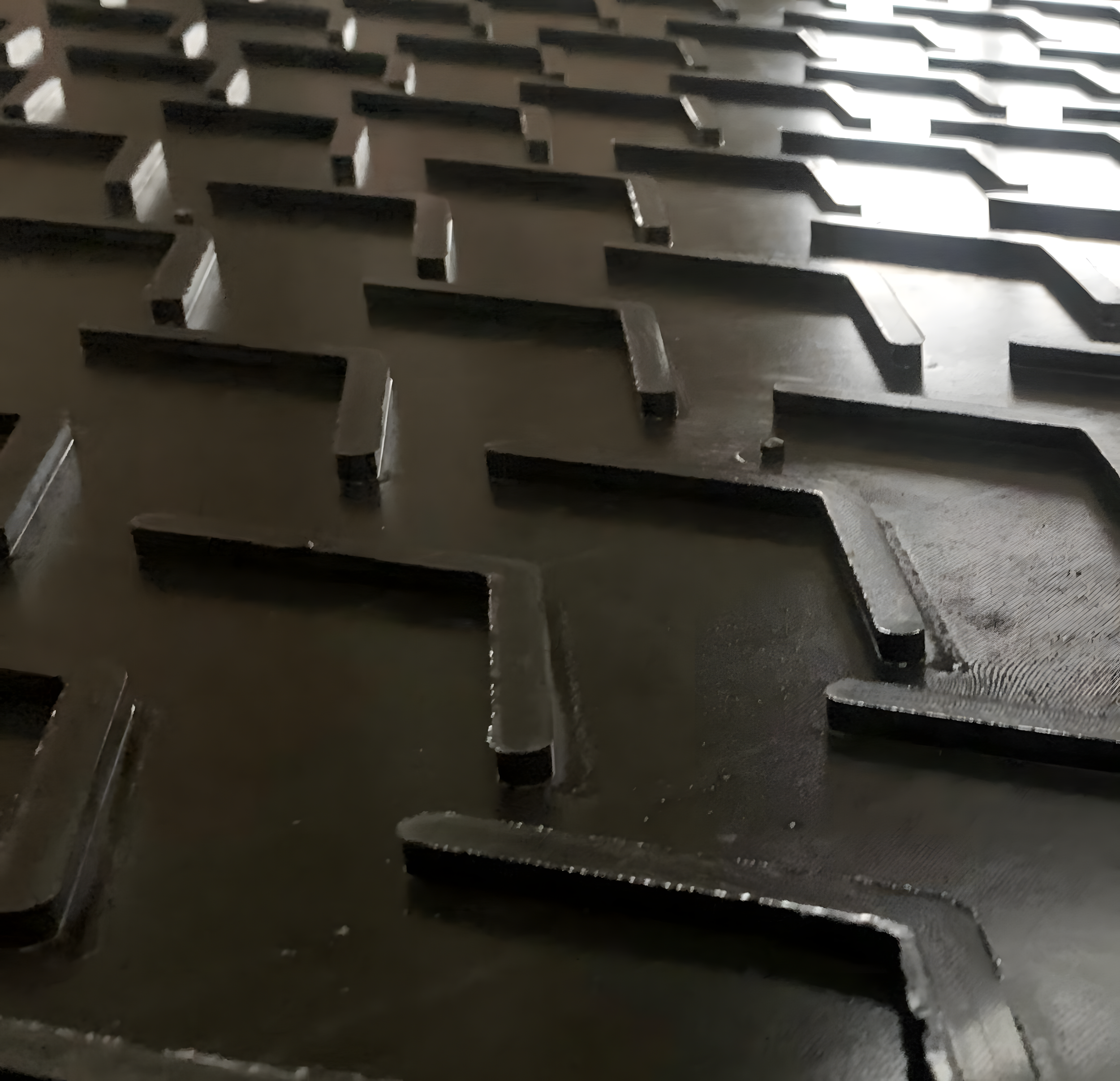Close-up of a stack of metal grates or vents with evenly spaced rectangular openings, casting shadows on a flat surface.