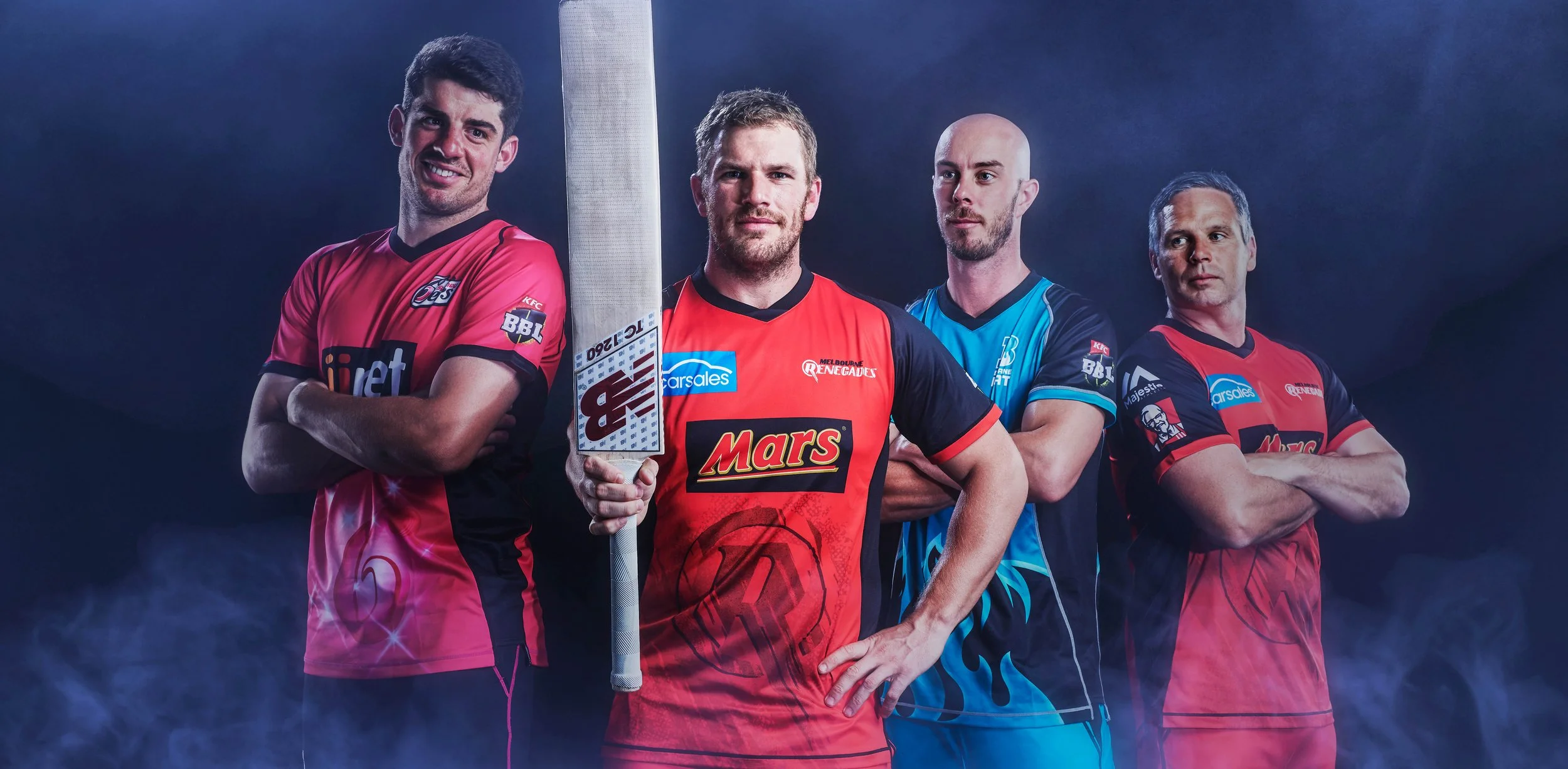Four Australian cricket players in colorful team uniforms posing with a cricket bat against a dark blue background