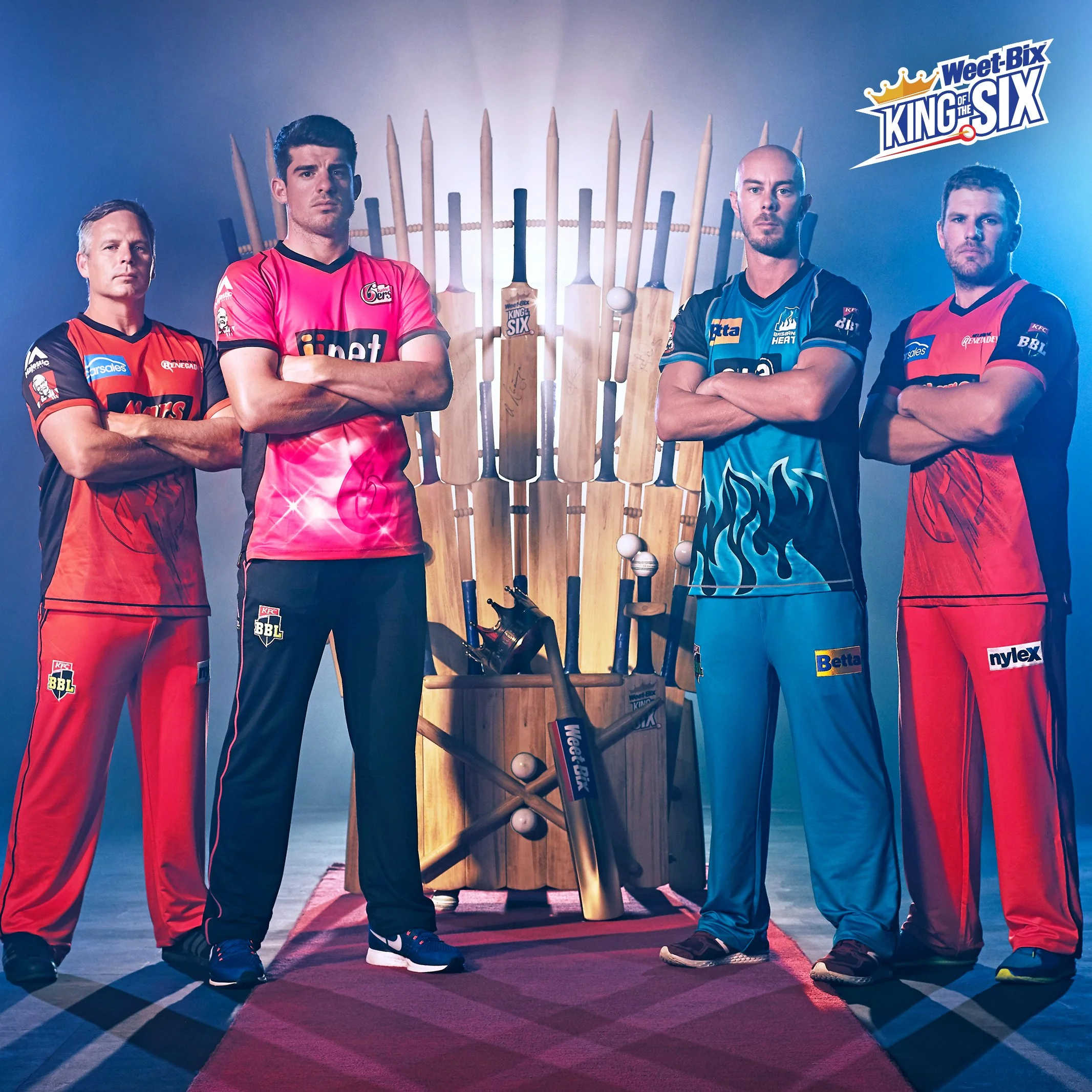 Four cricketers in colorful uniforms pose beside cricket bats beneath a West-Bix King of the Six logo.