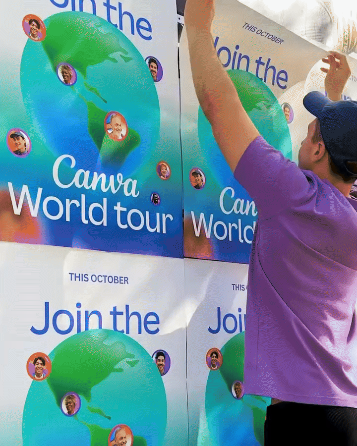 Person in a purple shirt installing Canva World Tour promotional posters featuring a colorful globe and diverse faces.