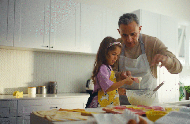 Father and daughter preparing food together in a bright kitchen