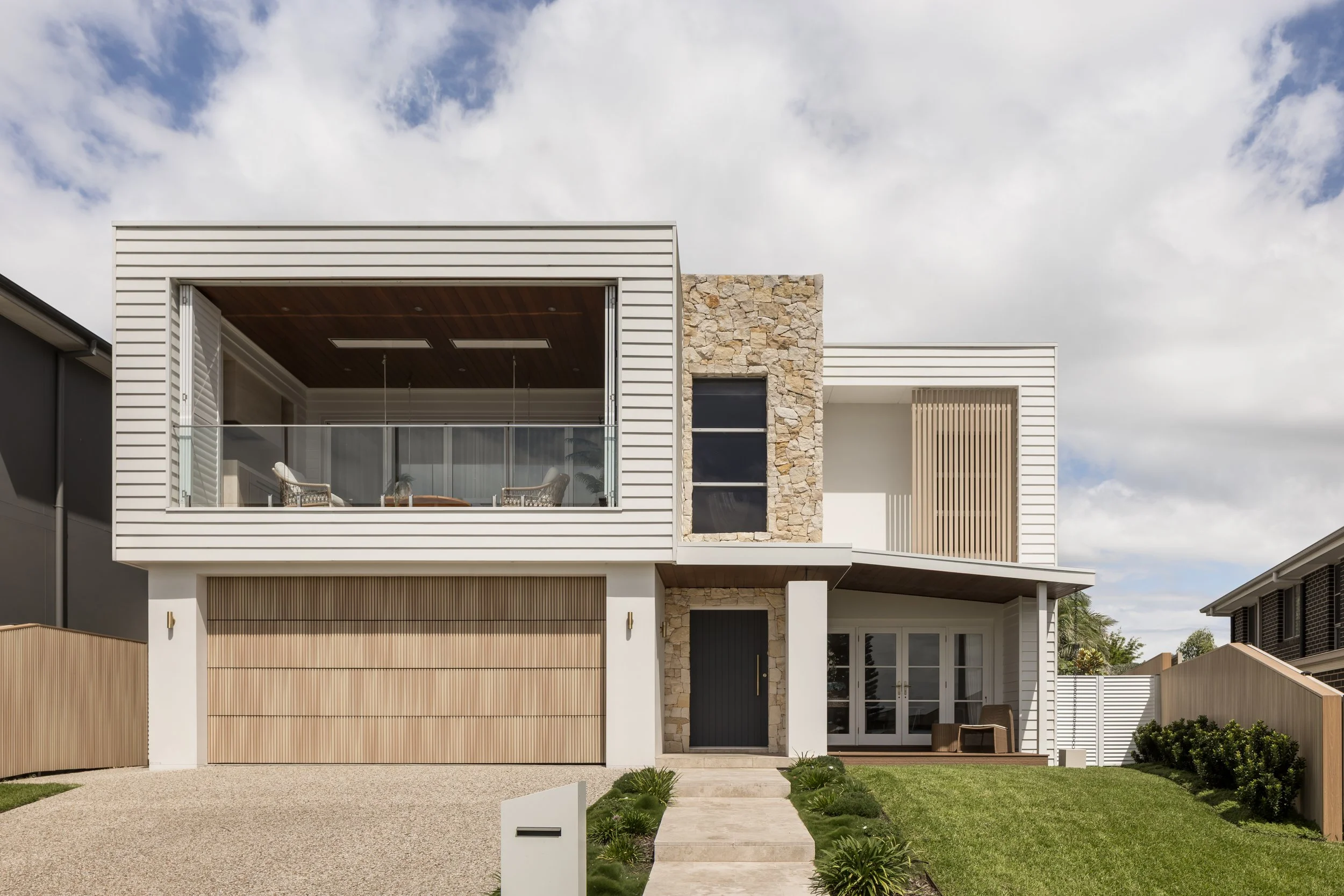 Coastal home facade with white weatherboard and natural stone, Shell Cove home renovation