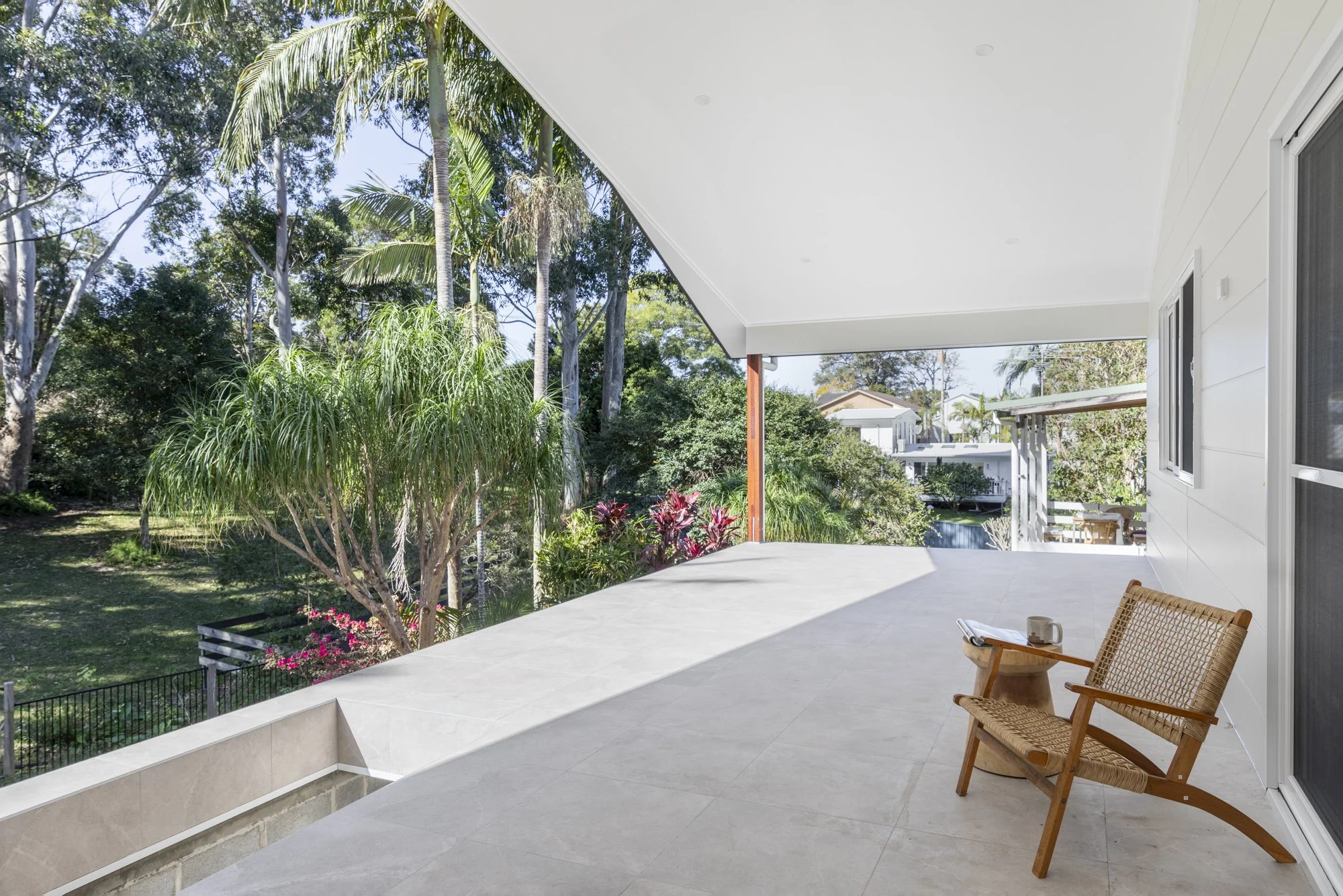 Large covered tiled deck framed by an established garden, Corrimal extension