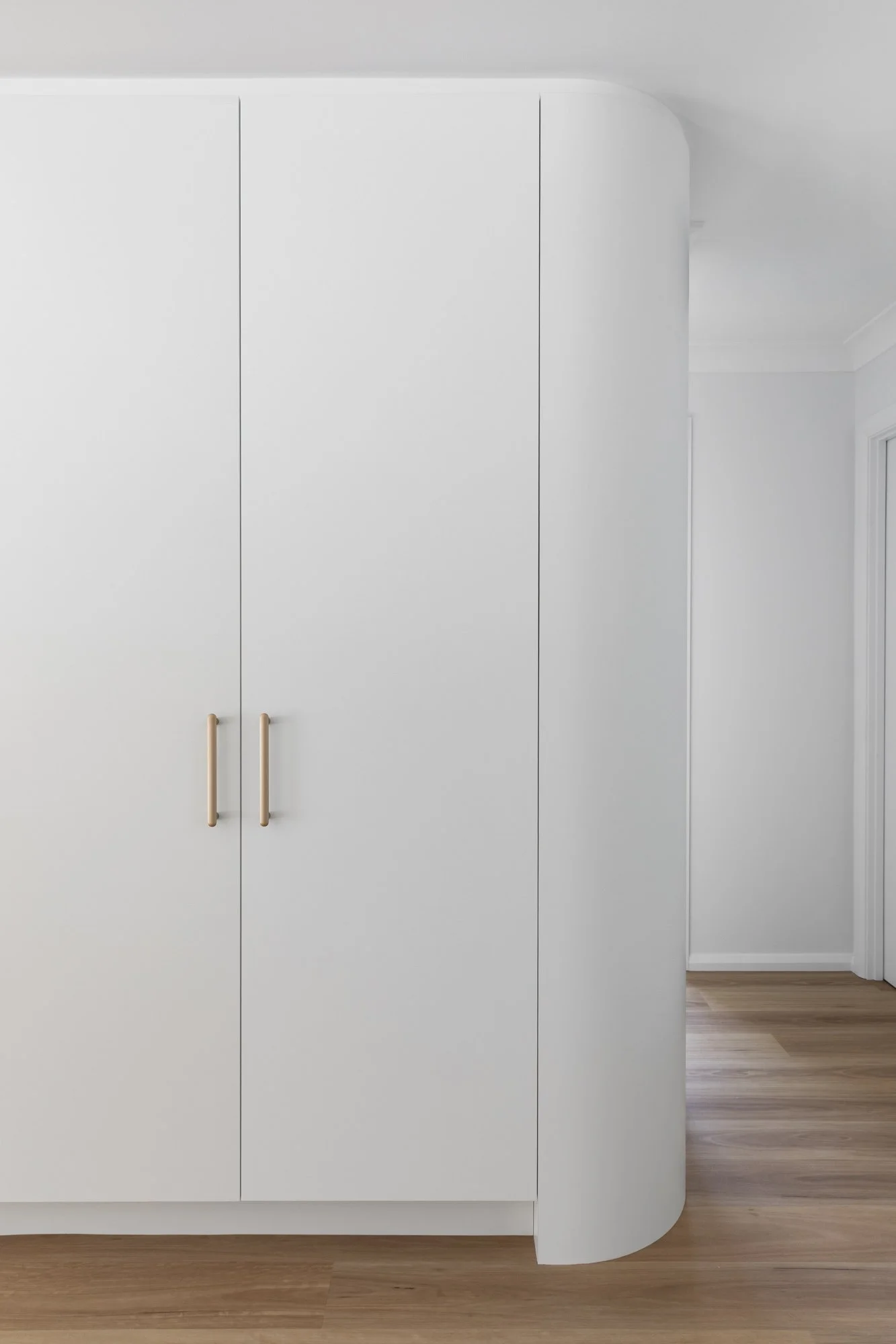 Curved white joinery with timber handles, Corrimal home extension