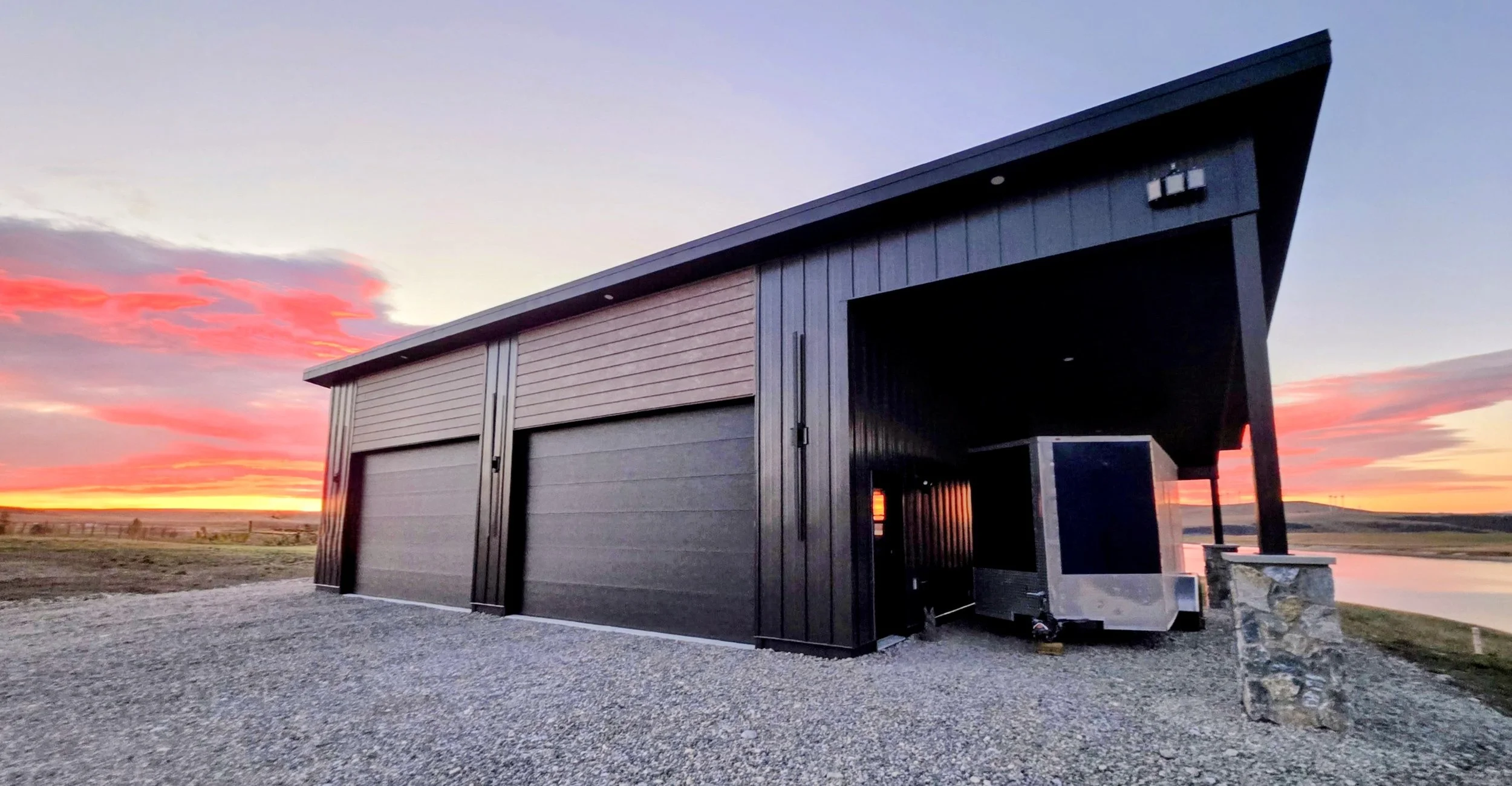 A modern black garage with a mountain and sunset background.