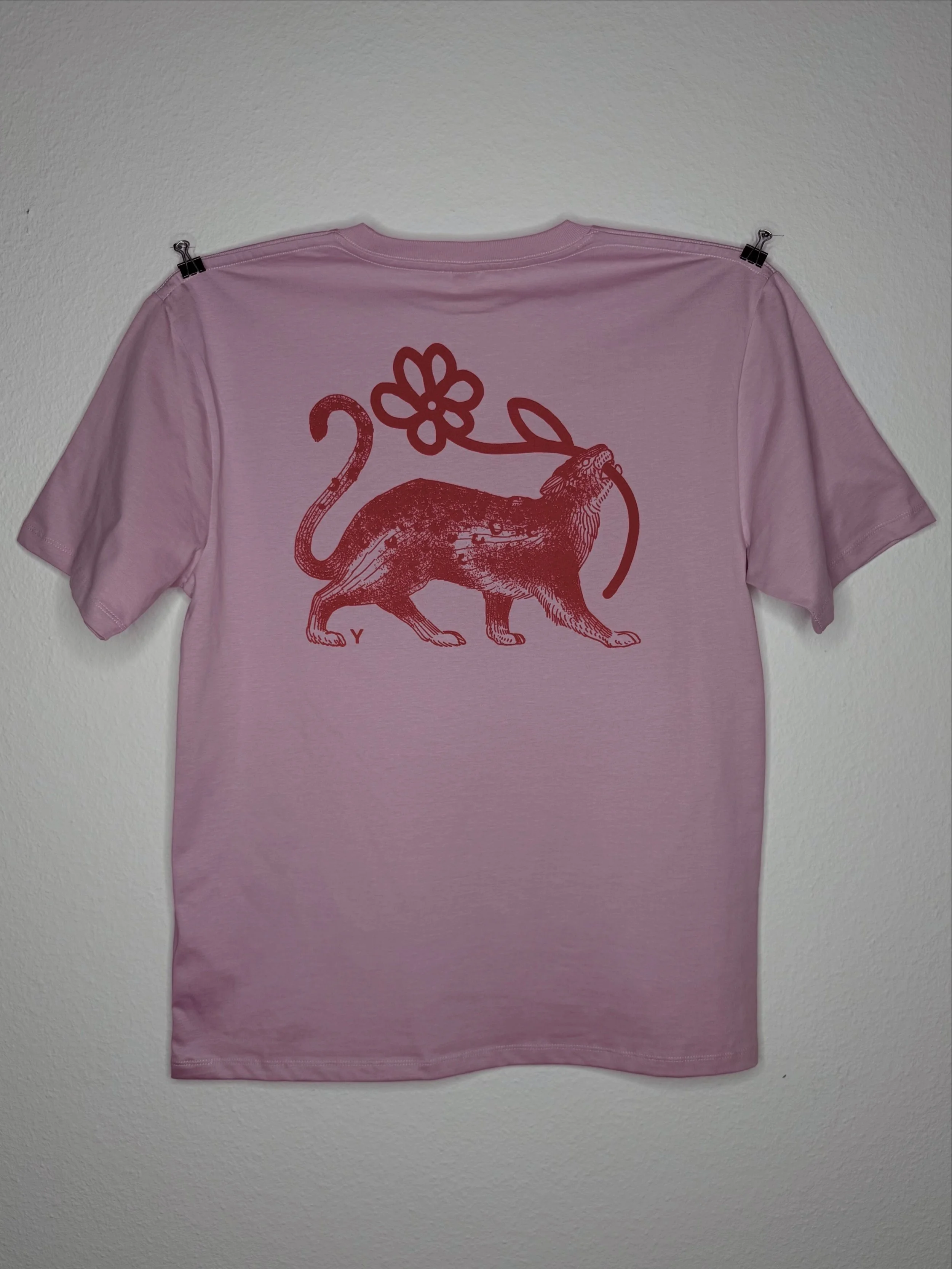 Rosa T-Shirt mit rotem Vintage-Aufdruck eines Leopards mit Blume, an einer Wand befestigt.