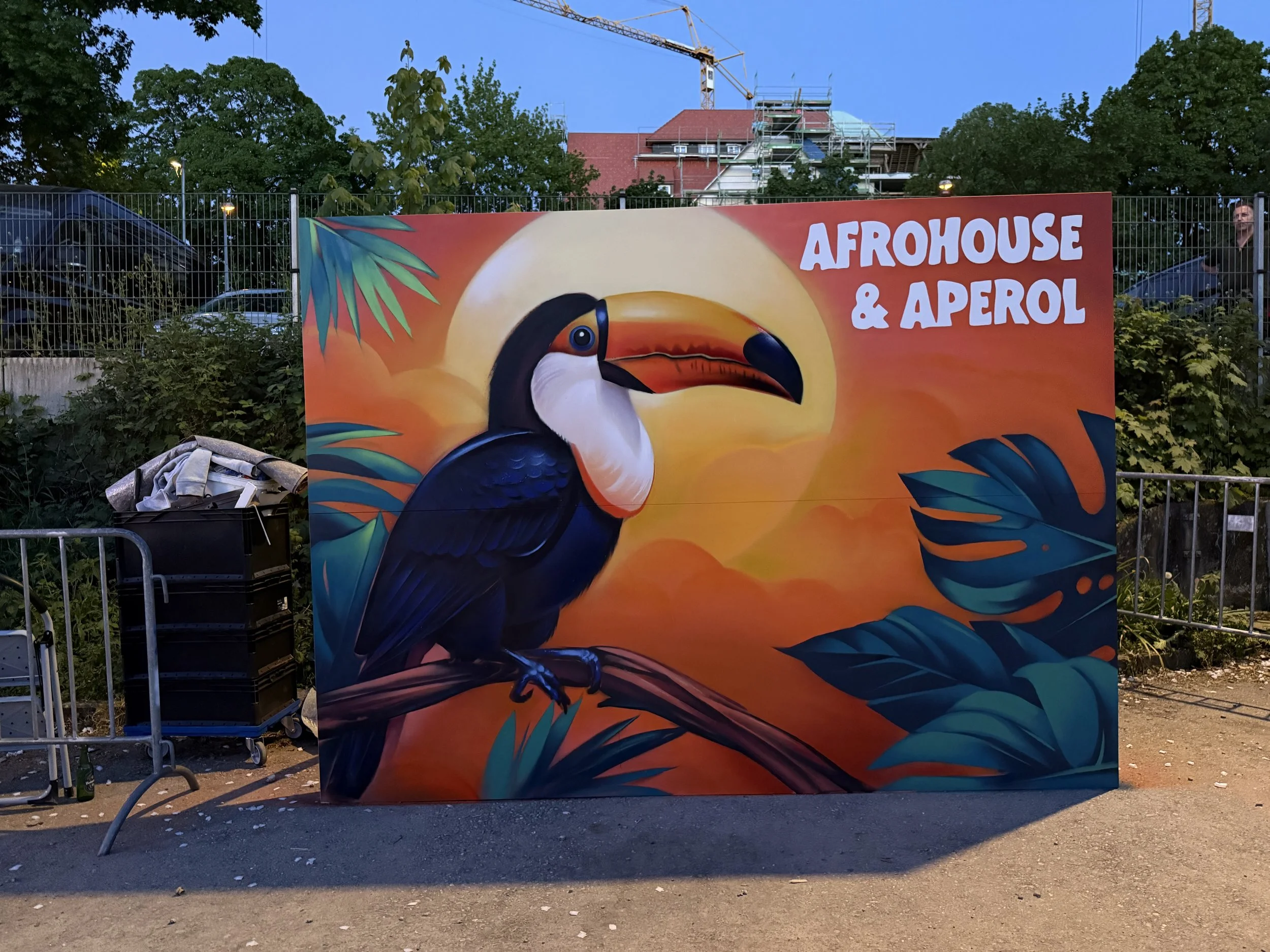 Ein buntes Graffiti mit einem Tukane und Palmenblättern, das den Text 'Afrohouse & Aperol' trägt.