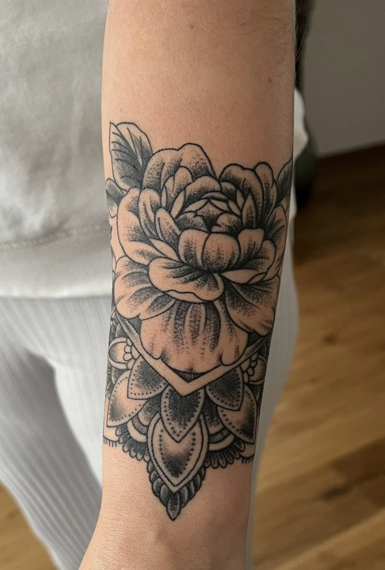 Detailaufnahme eines floralen Tattoos mit mehreren stilisierten Blüten und Blättern auf einem Unterarm.