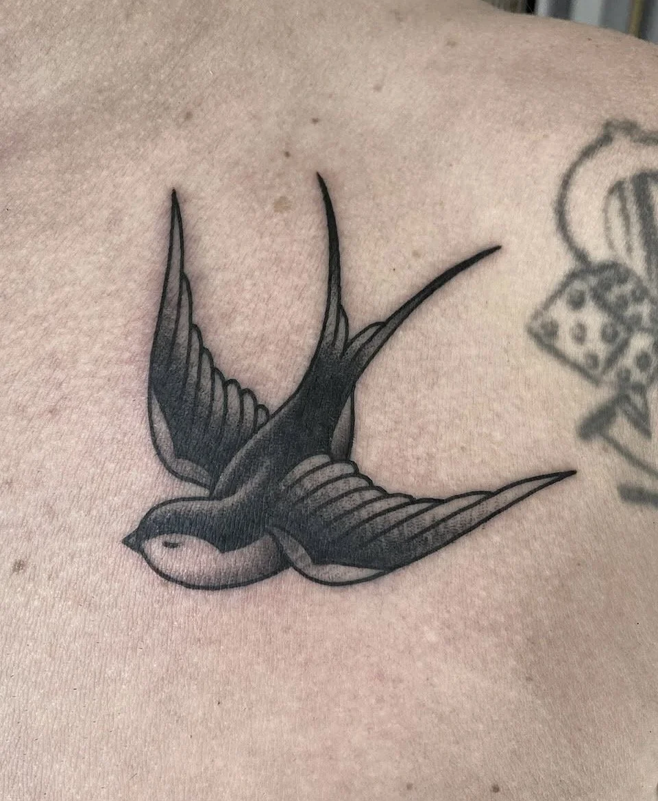 Schwarz-graues Tattoo von zwei fliegenden Schwalben auf der Haut