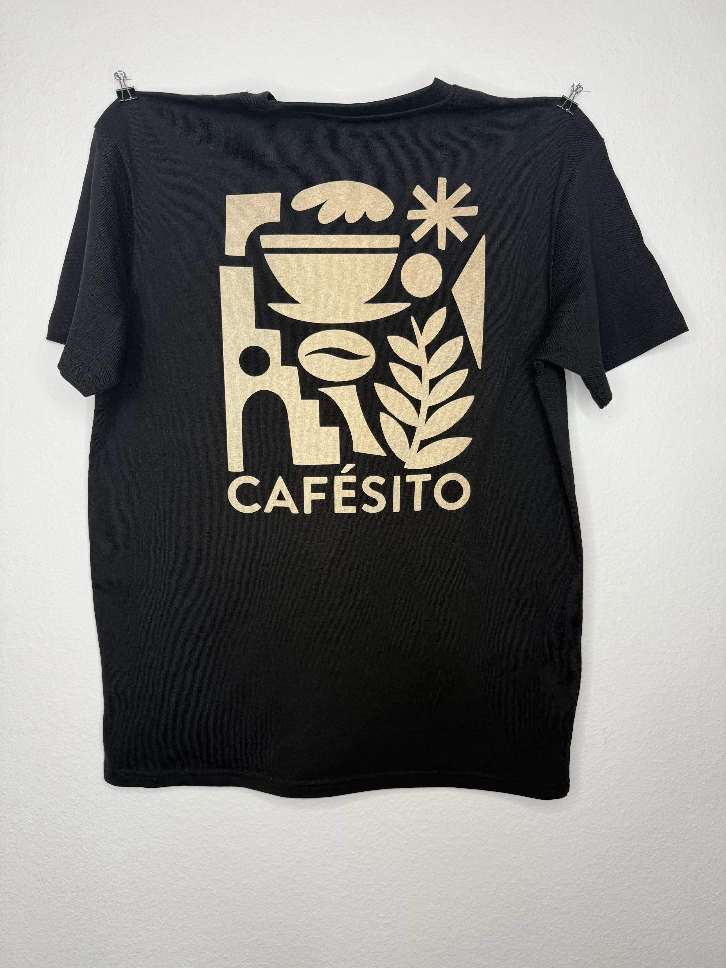 Schwarzes T-Shirt mit beigefarbenem, grafischem Kaffeetassenmotiv und dem Schriftzug „CAFÉSITO“.