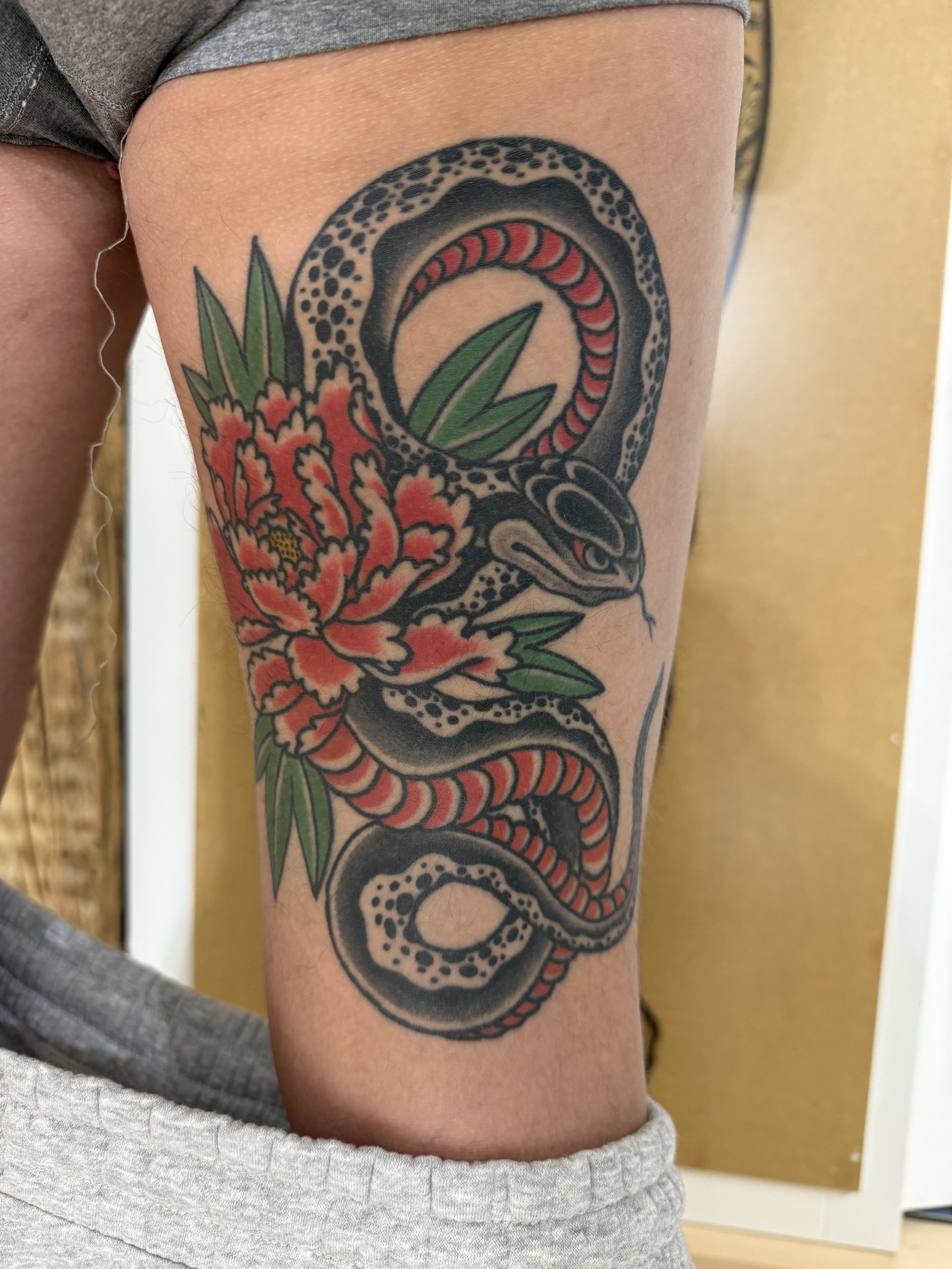 Nahaufnahme eines bunten japanischen Schlangen-Tattoos mit Pfingstrose.