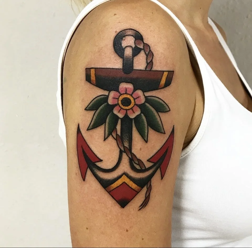Traditionelles Tattoo eines Old School Ankers auf weiblichem Oberarm