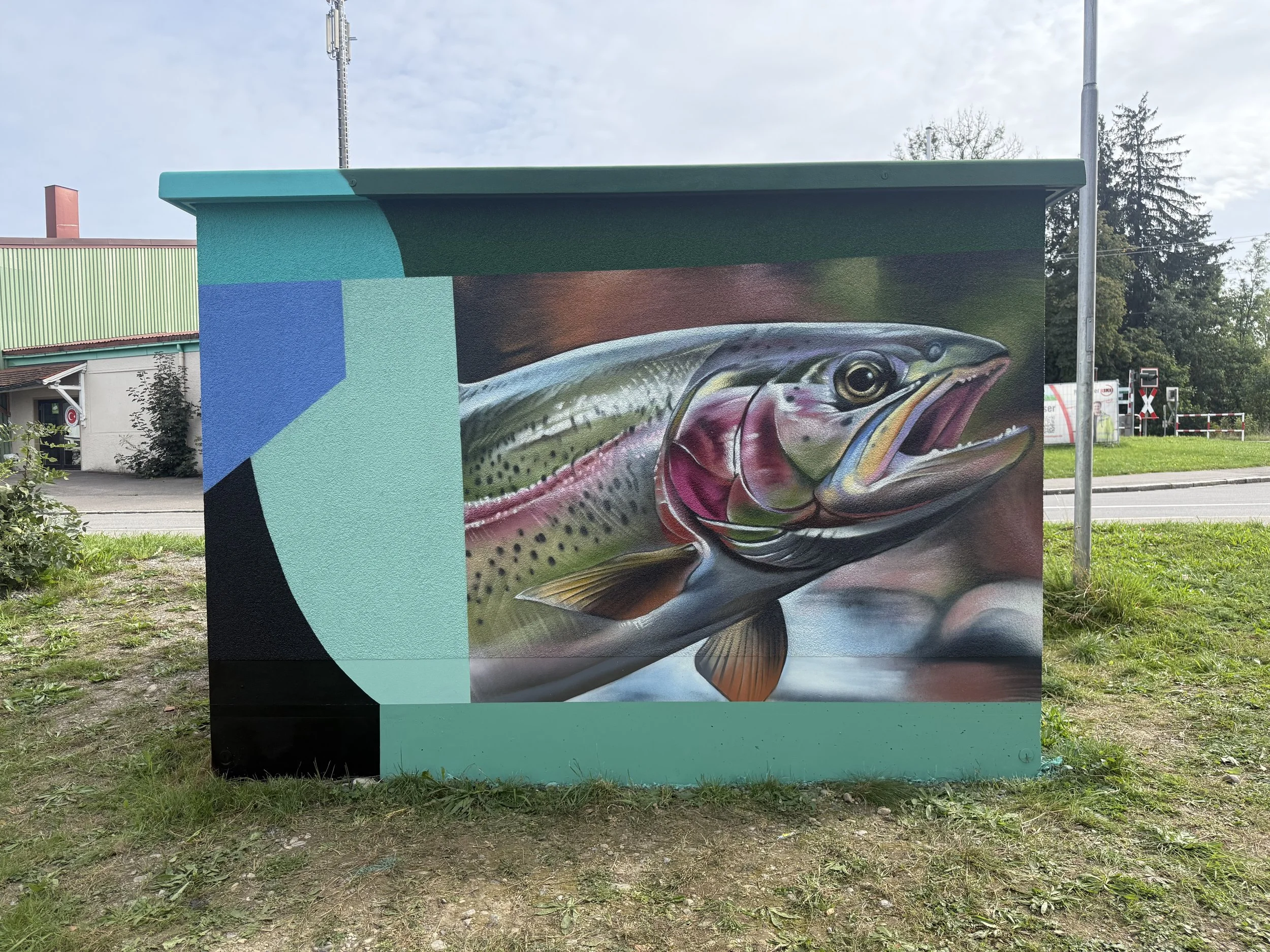 Wandgemälde eines Fisches in einer Stadt umgeben von Gebäuden und Bäumen