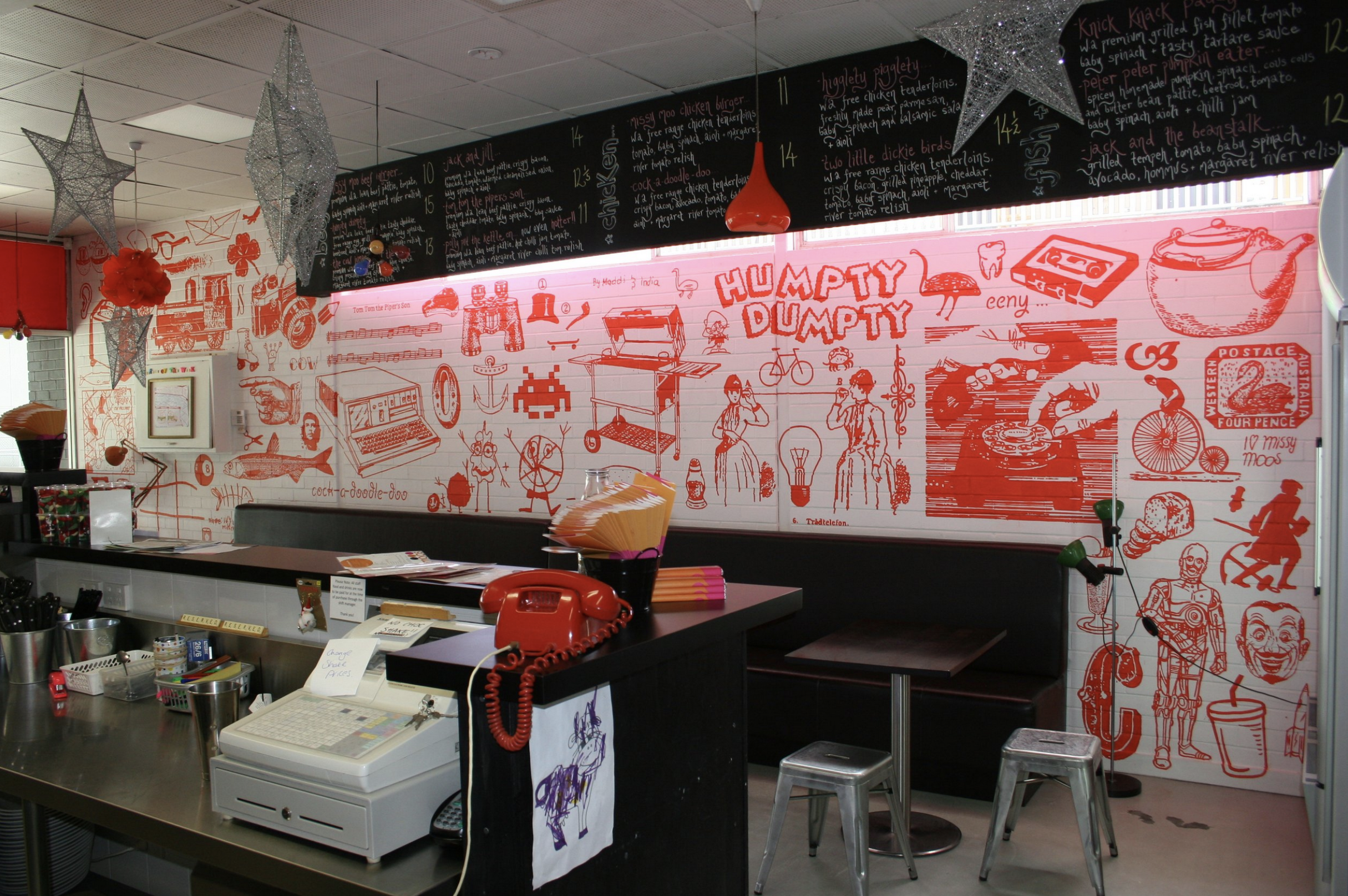 Innenansicht eines farbenfrohen Restaurants mit handgemalten Wandillustrationen.