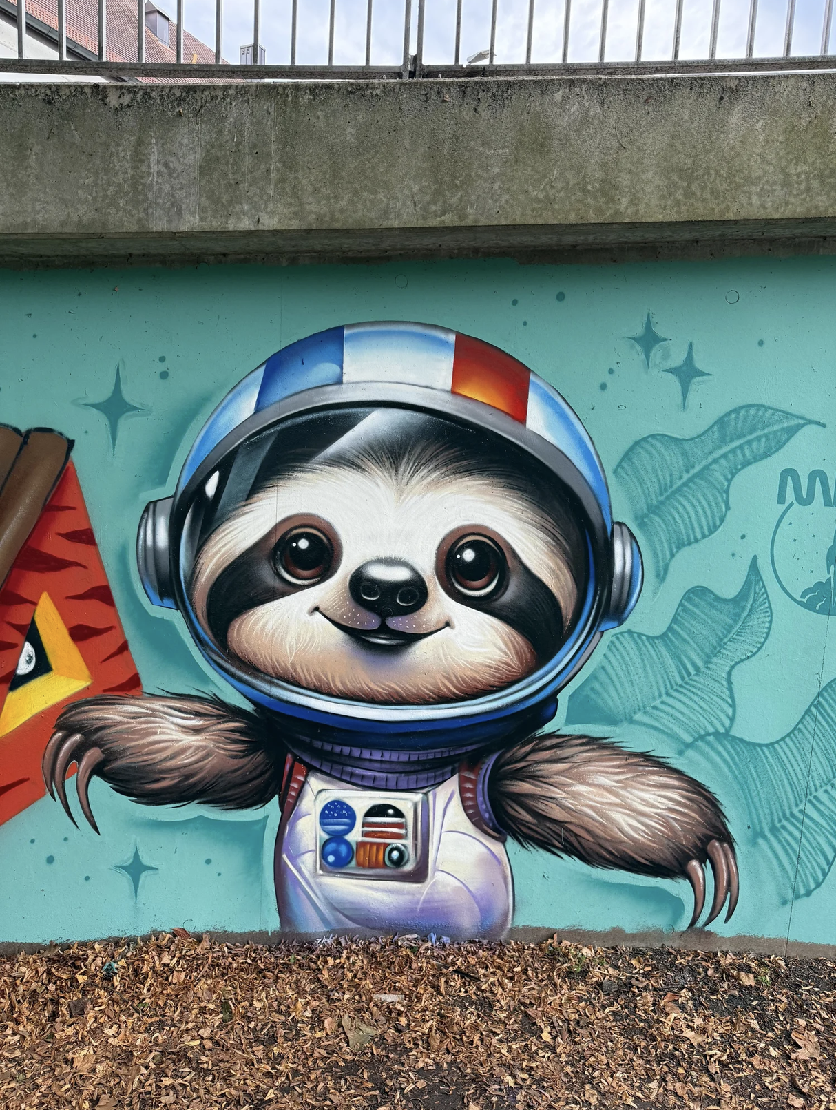 Graffiti eines niedlichen Faultiers in einem Raumanzug mit Helm auf einer Wand.