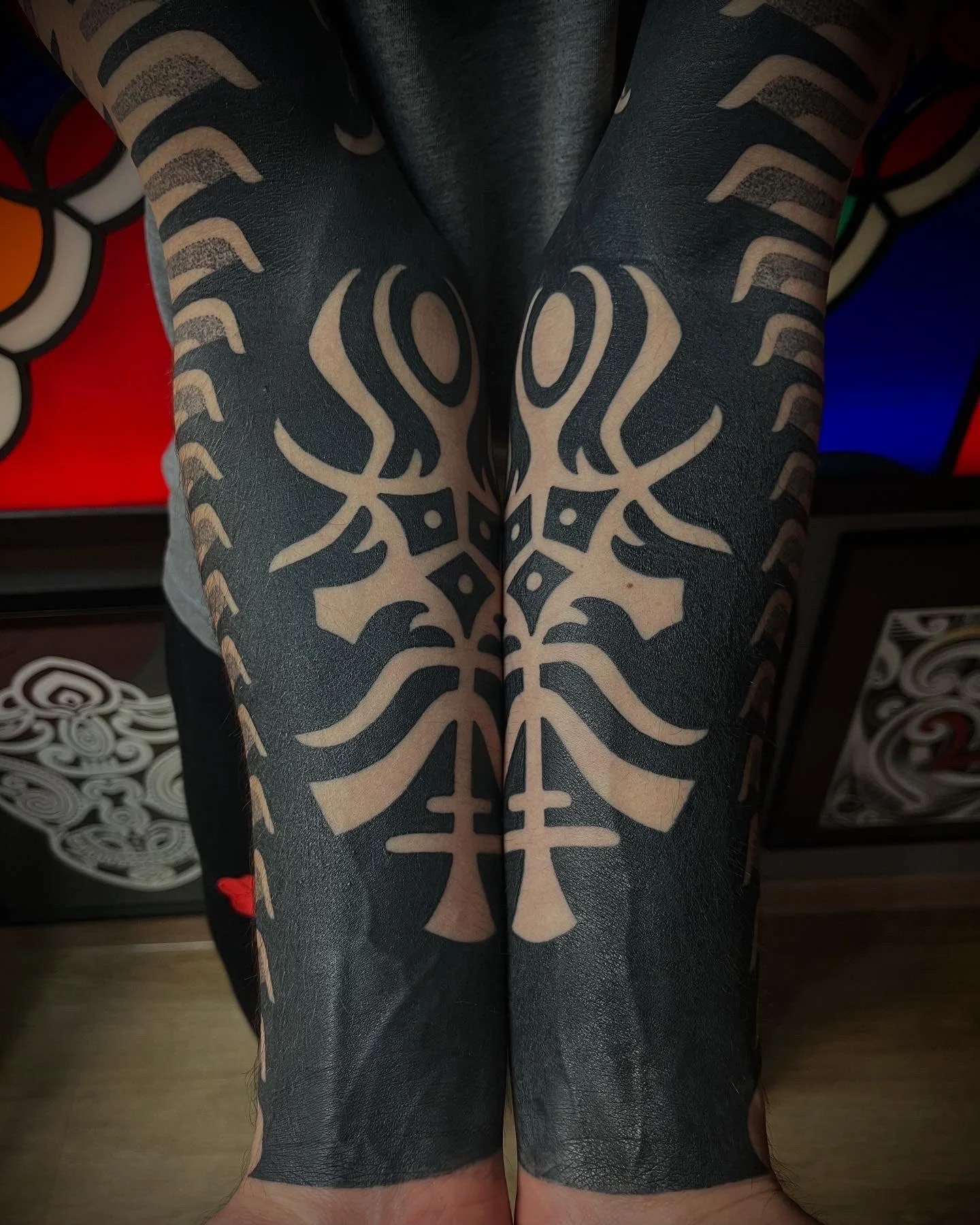 Nahaufnahme eines symmetrischen schwarzen Blackwork Tattoos im Dotwork Stil und Ornamentmotiv auf beiden Unterschenkeln.