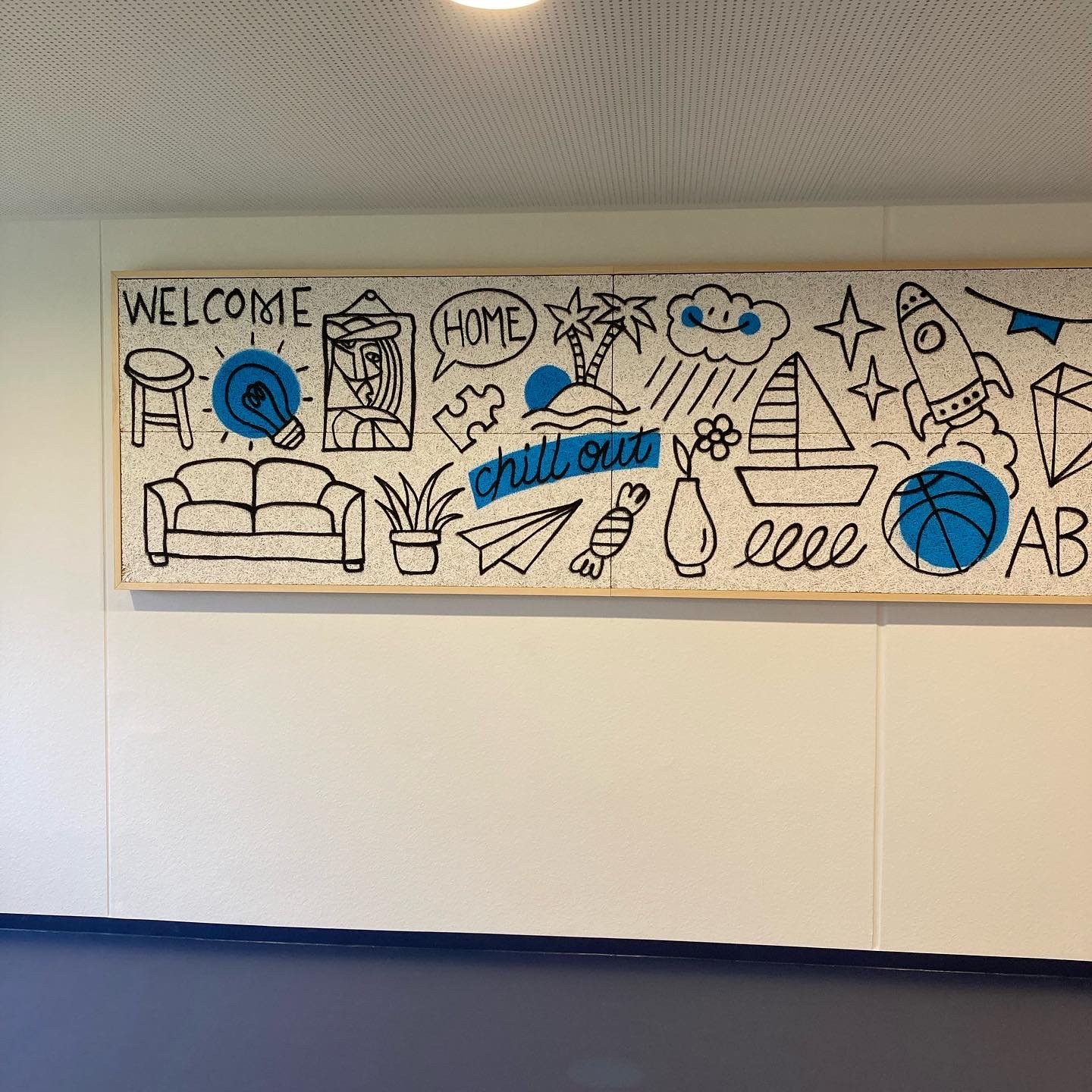 Skizzierte Wanddekoration mit Worten und Symbolen, darunter 'Welcome', 'Home', 'chill out', ein Sofa, eine Palme, ein Helikopter, ein Basketball, ein Papierflugzeug und andere Illustrationen in Schwarz mit blauen Akzenten.