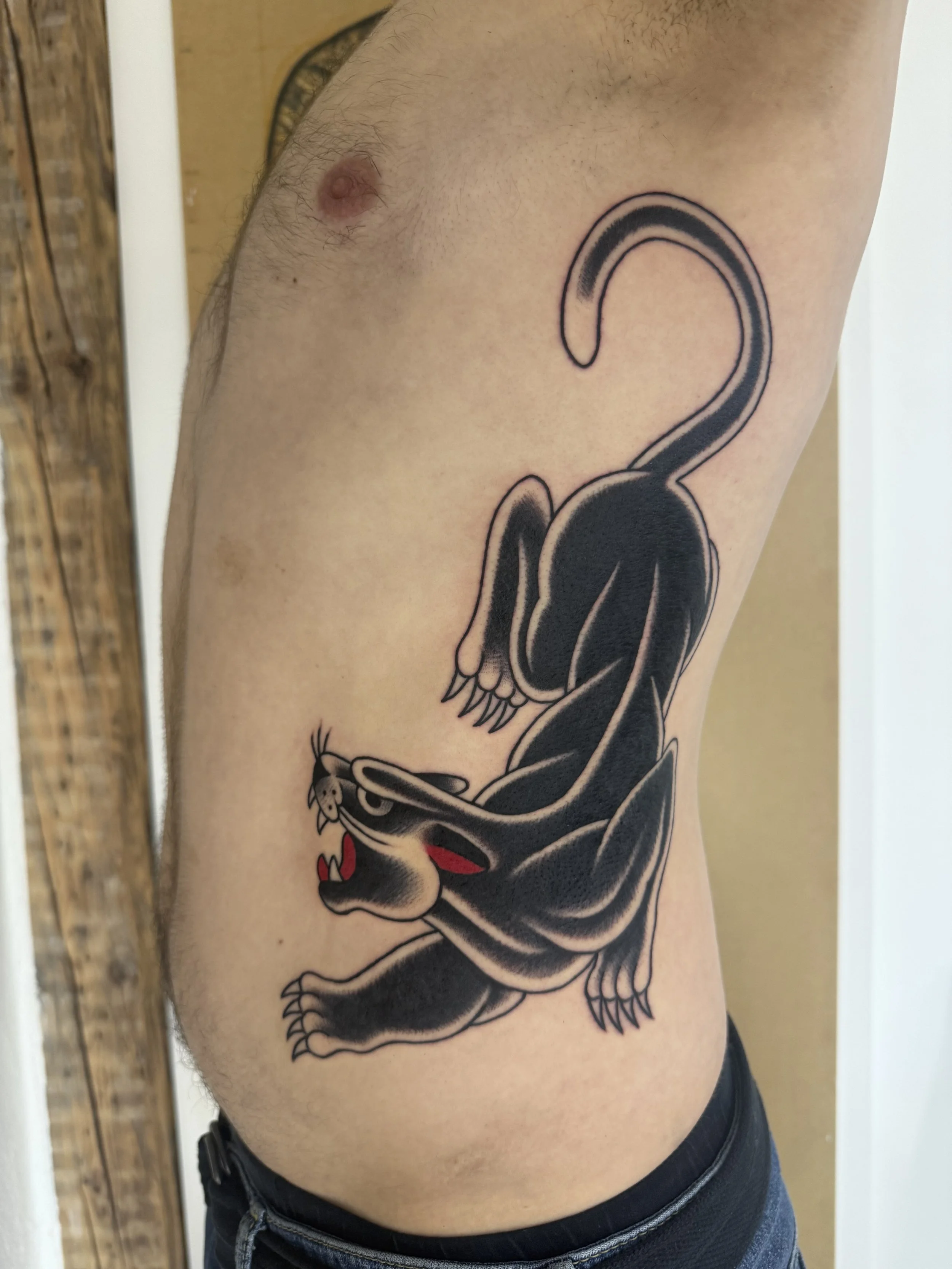 Nahaufnahme einer Person mit traditional Panther Tattoo auf den Rippen 