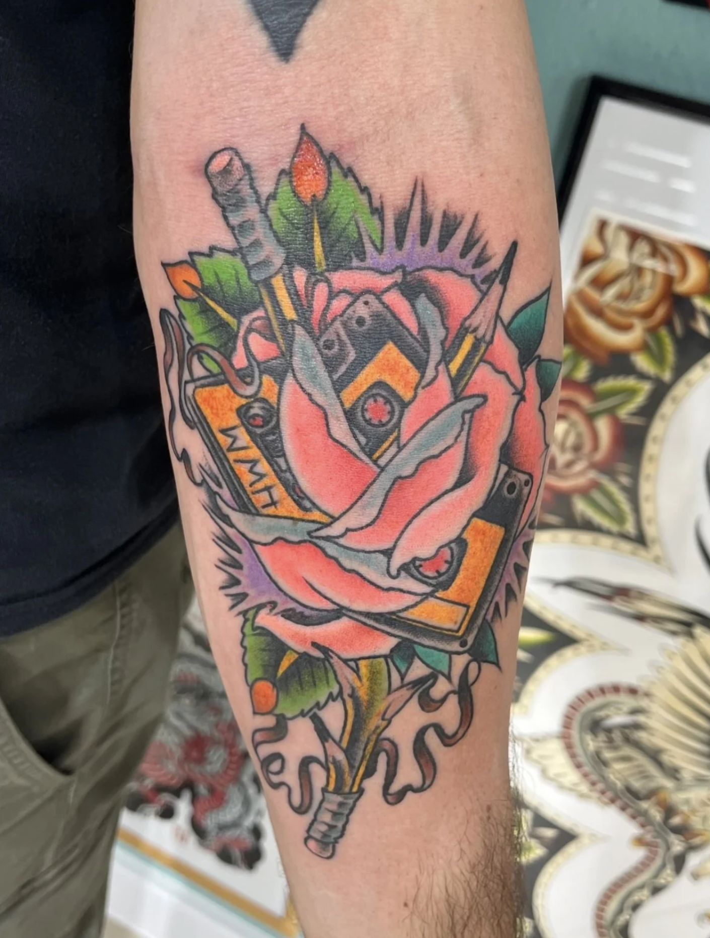 Buntes Tattoo mit Rose, Kerze, Totenkopf, Schlangen und Streichhölzern auf einem Unterarm