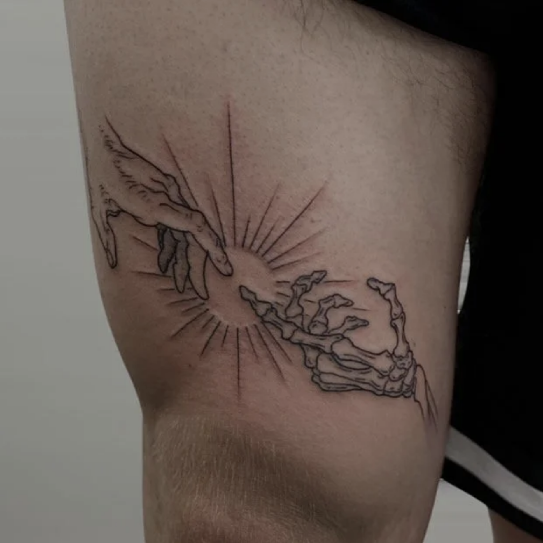 Tattoo mit zwei fliegenden Kranichen, strahlenförmigem Sonnenmotiv und stilisierten Wolken auf einem Oberarm