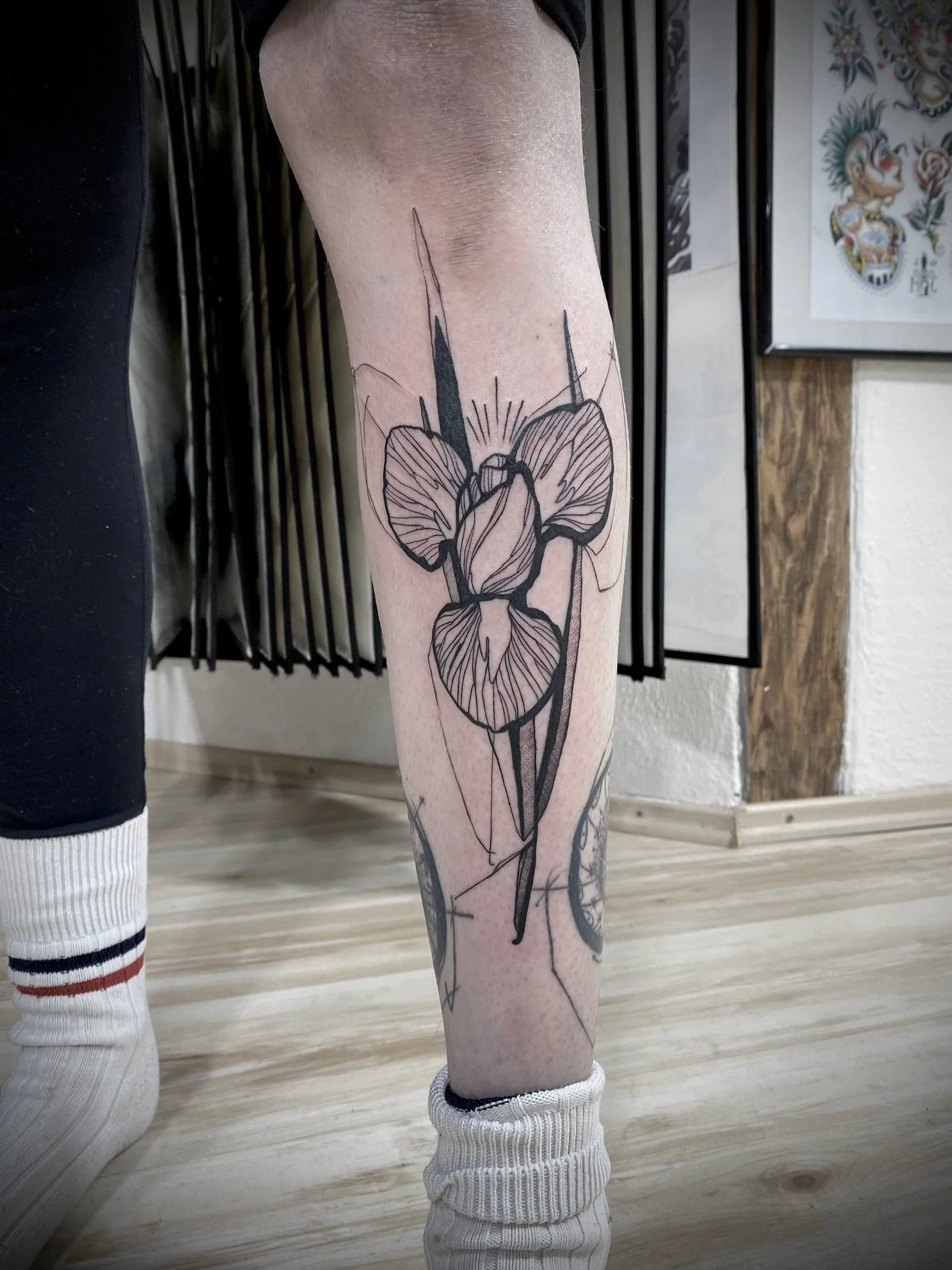Nahaufnahme eines Beins mit floralem Tattoo aus stilisierten Blüten und Blättern