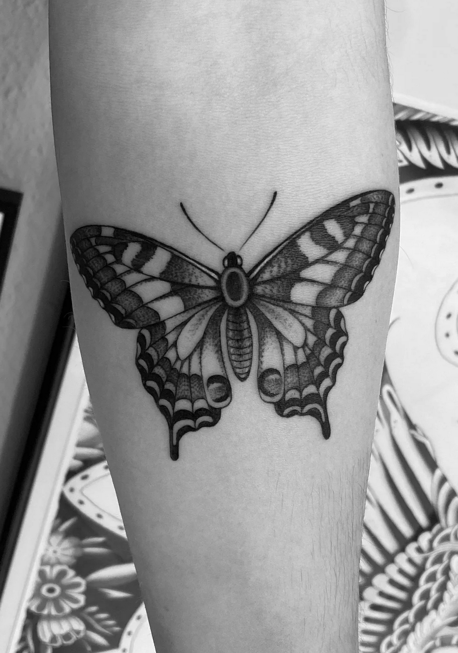 Schwarz-weißes Schmetterling-Tattoo mit detaillierten Flügelmustern auf einem Arm